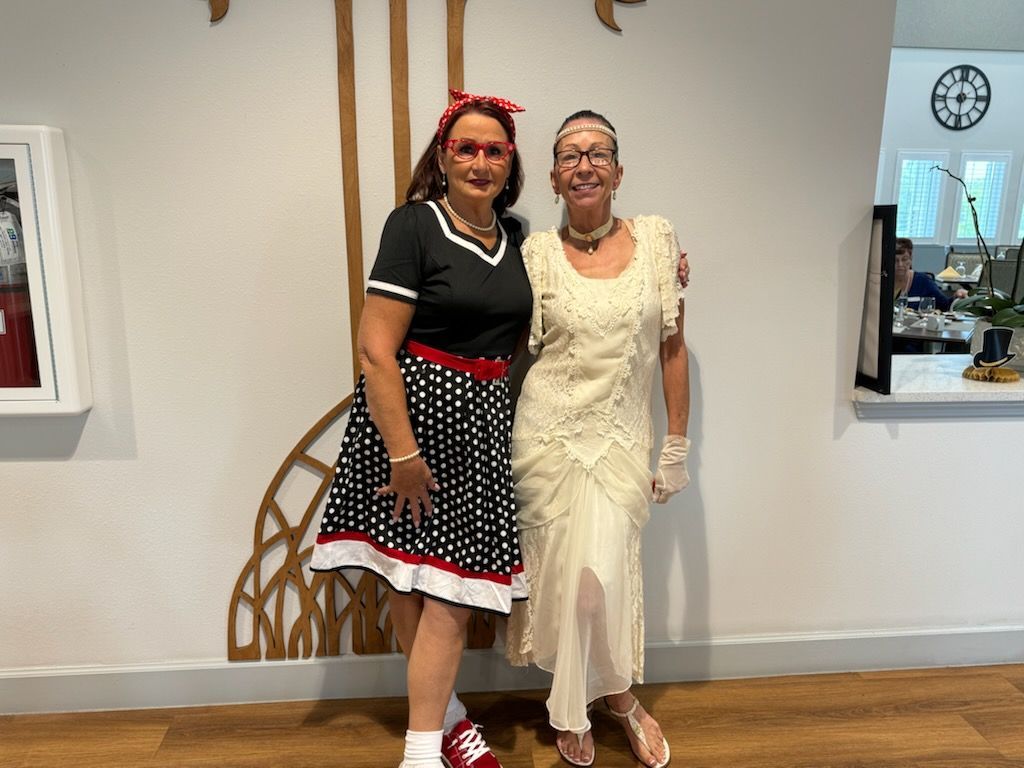 Two people in costume posing by a wall