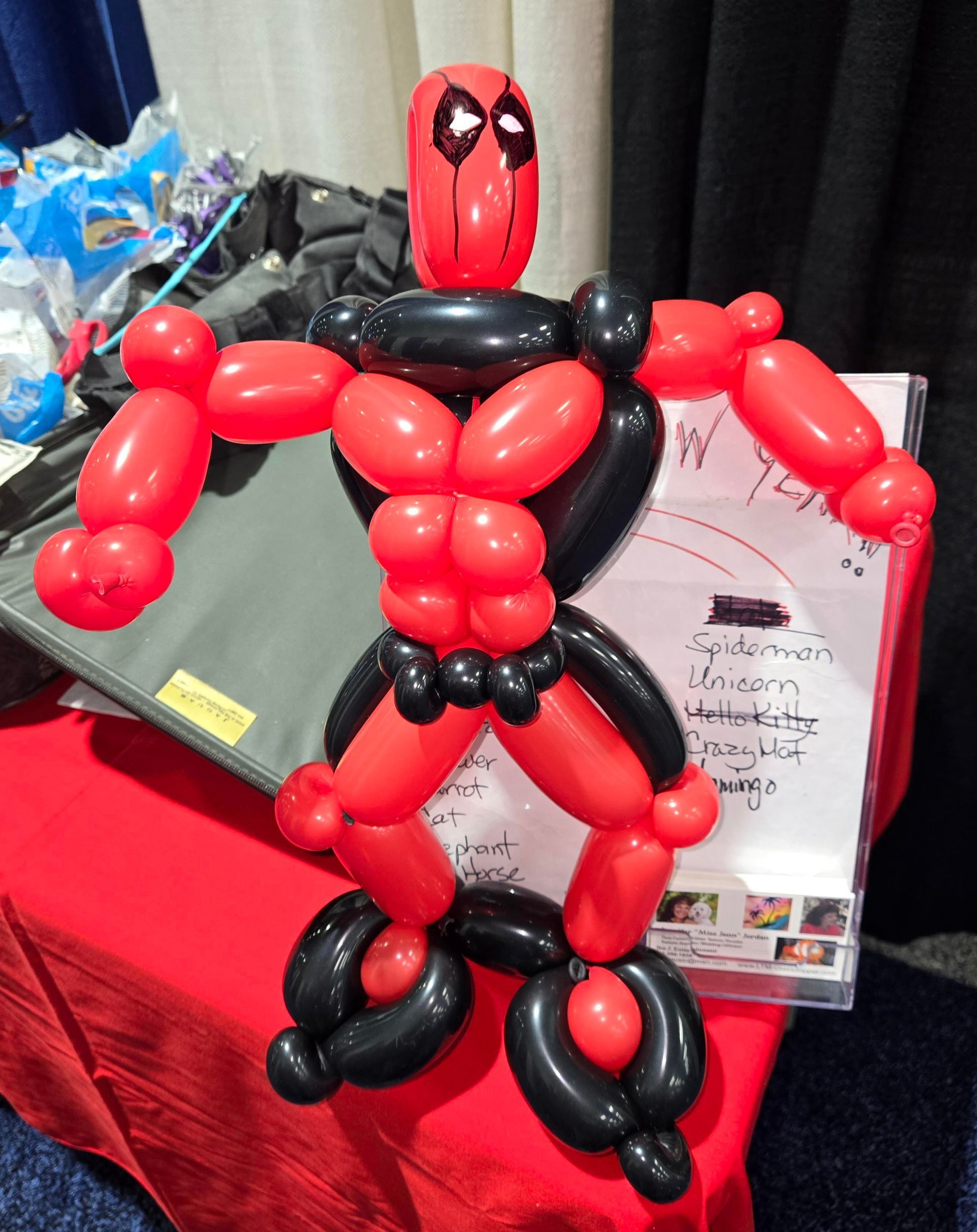 A Deadpool figure made of red and black balloons, standing on a red surface.