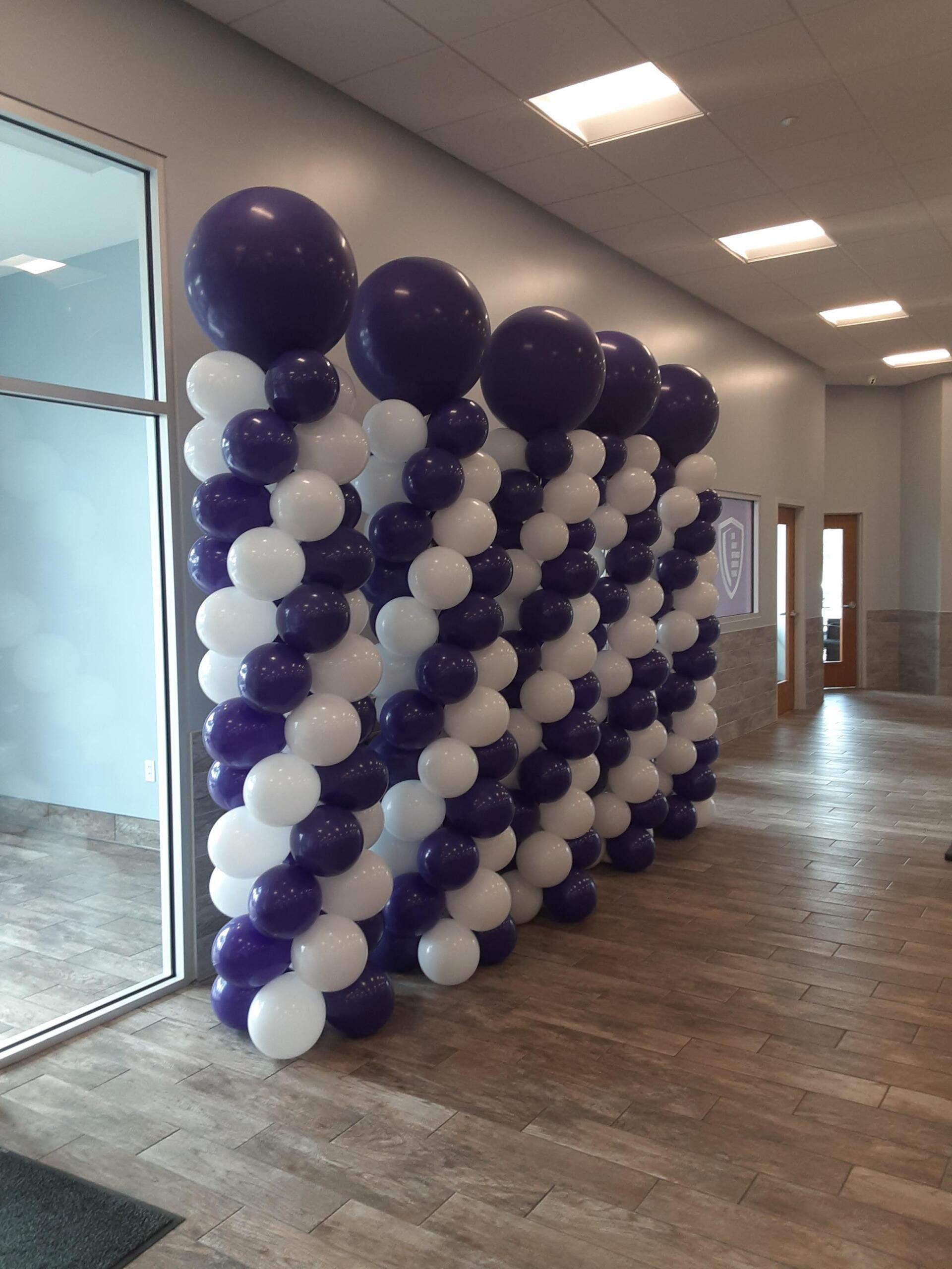 A row of purple and white balloons in a hallway