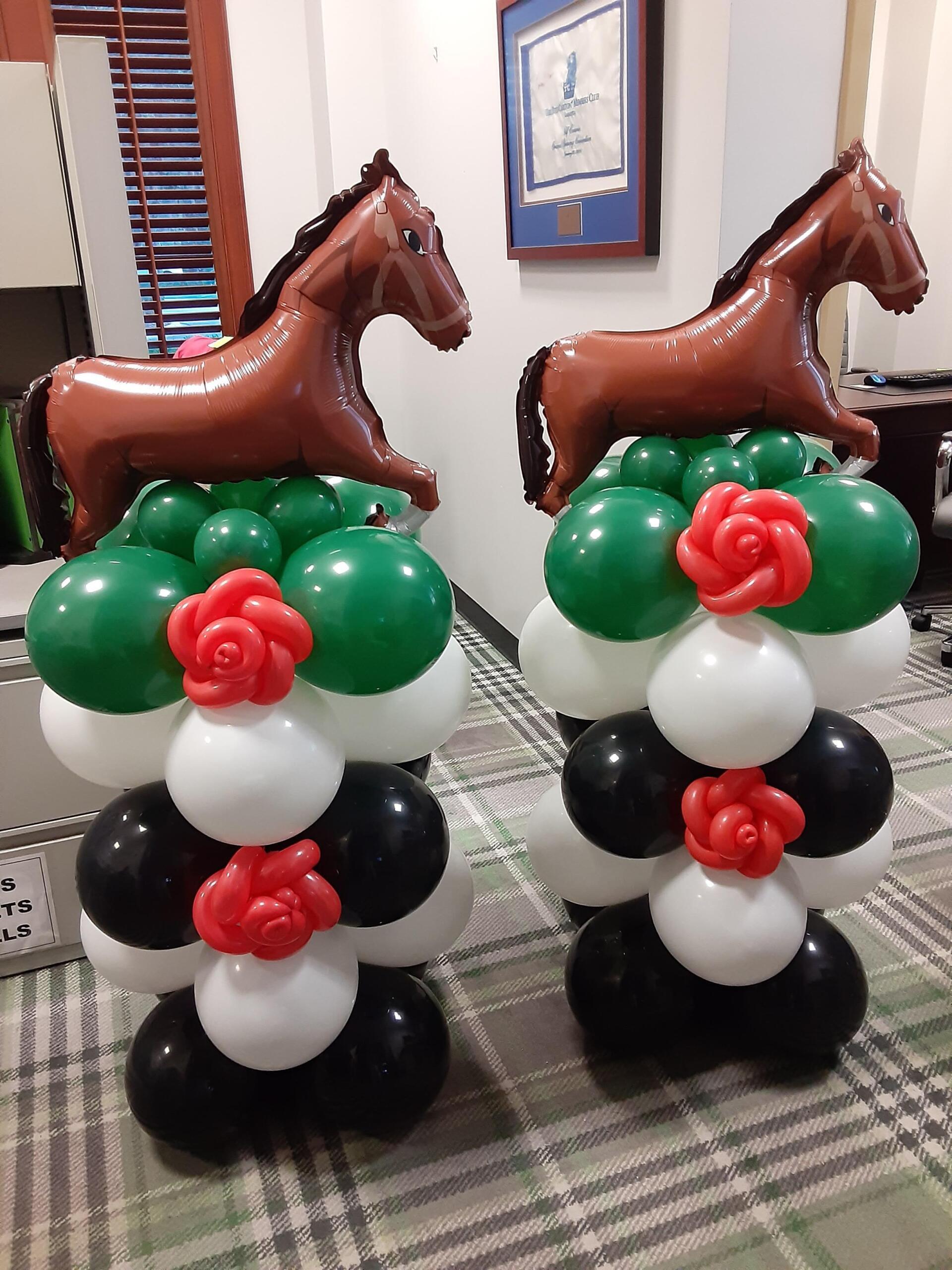 Two horse balloons are sitting on top of a bunch of balloons