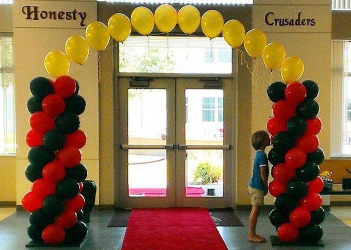 A boy stands under a balloon arch that says honesty and crusaders
