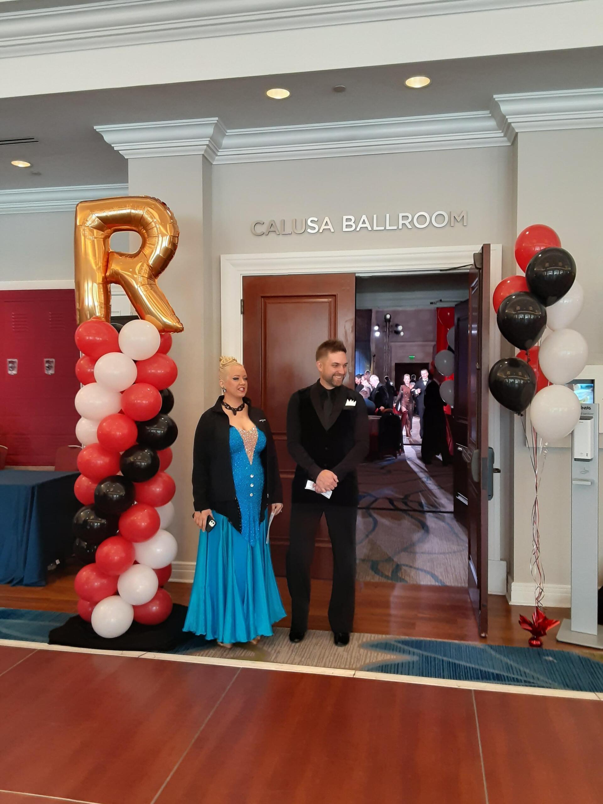 A woman in a blue dress is standing next to a man in a tuxedo