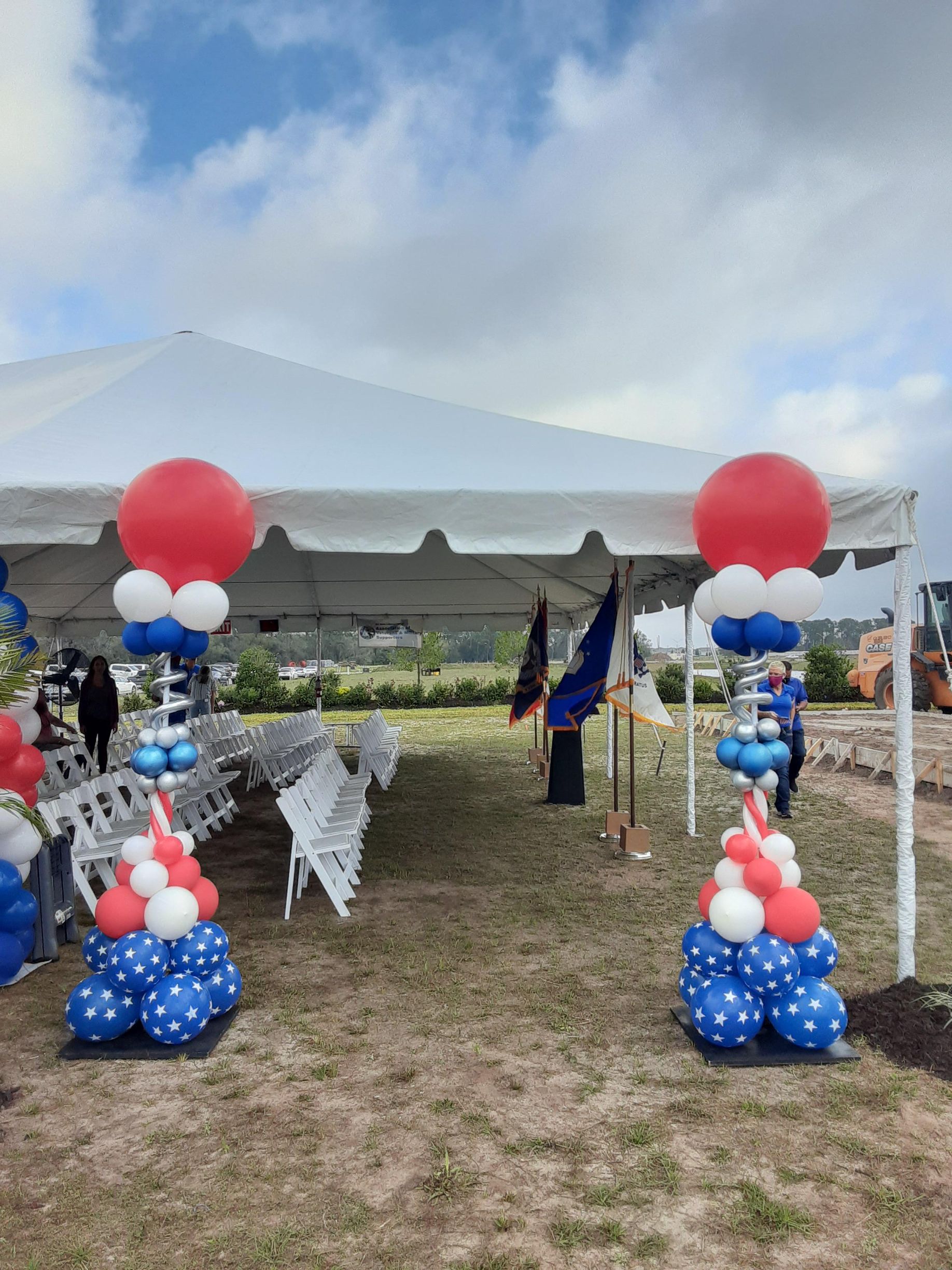 A tent is decorated with red , white and blue balloons.