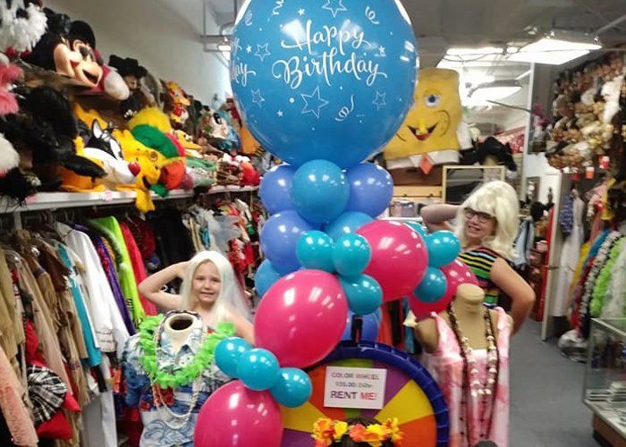 A happy birthday balloon is surrounded by pink and blue balloons