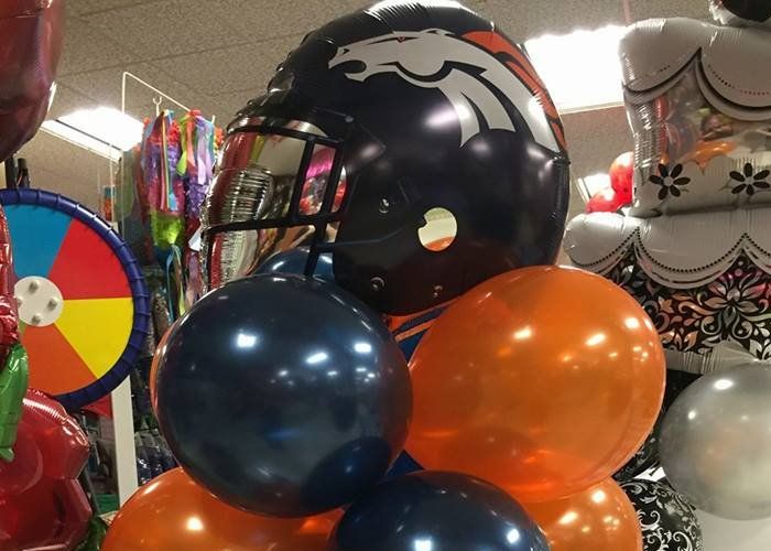 A broncos helmet is surrounded by balloons in a store