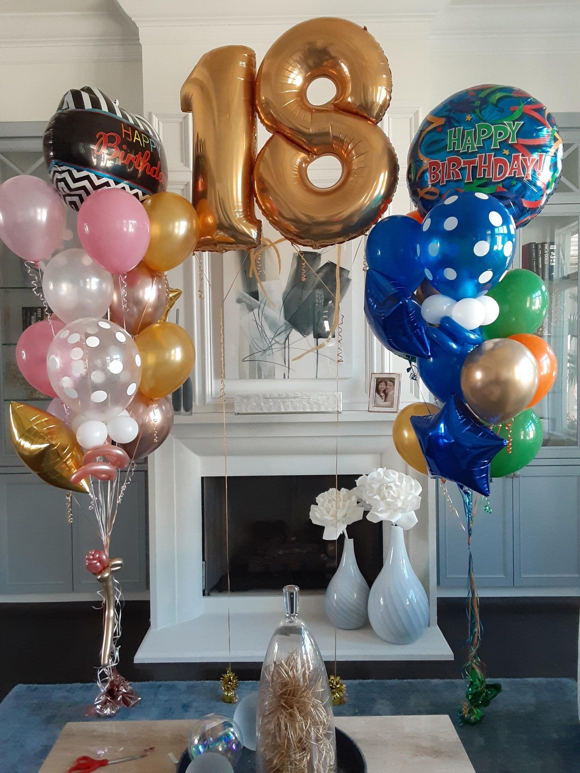 A bunch of balloons are sitting on a table in front of a fireplace.