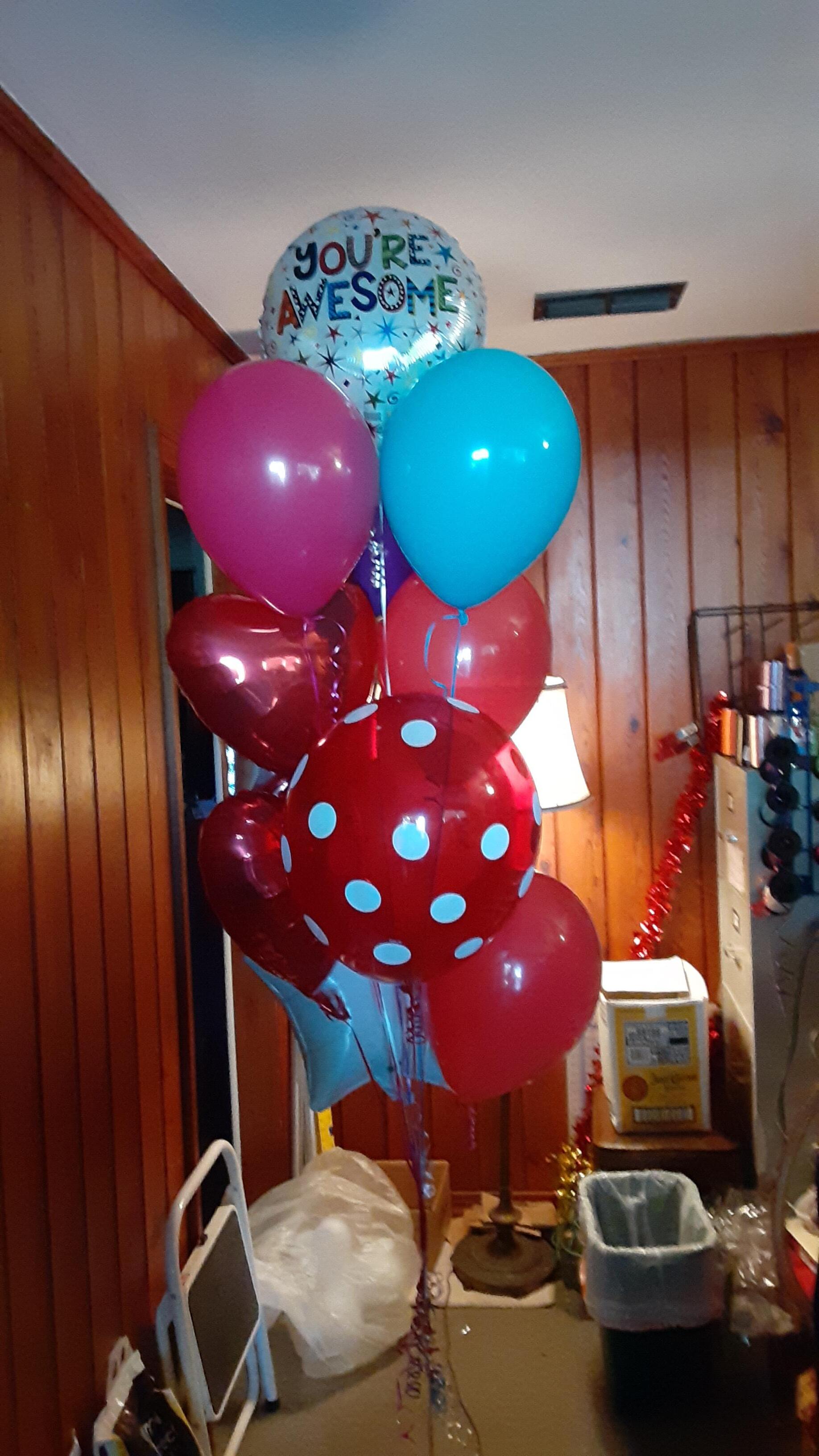 A bunch of balloons are sitting on a table in a room.