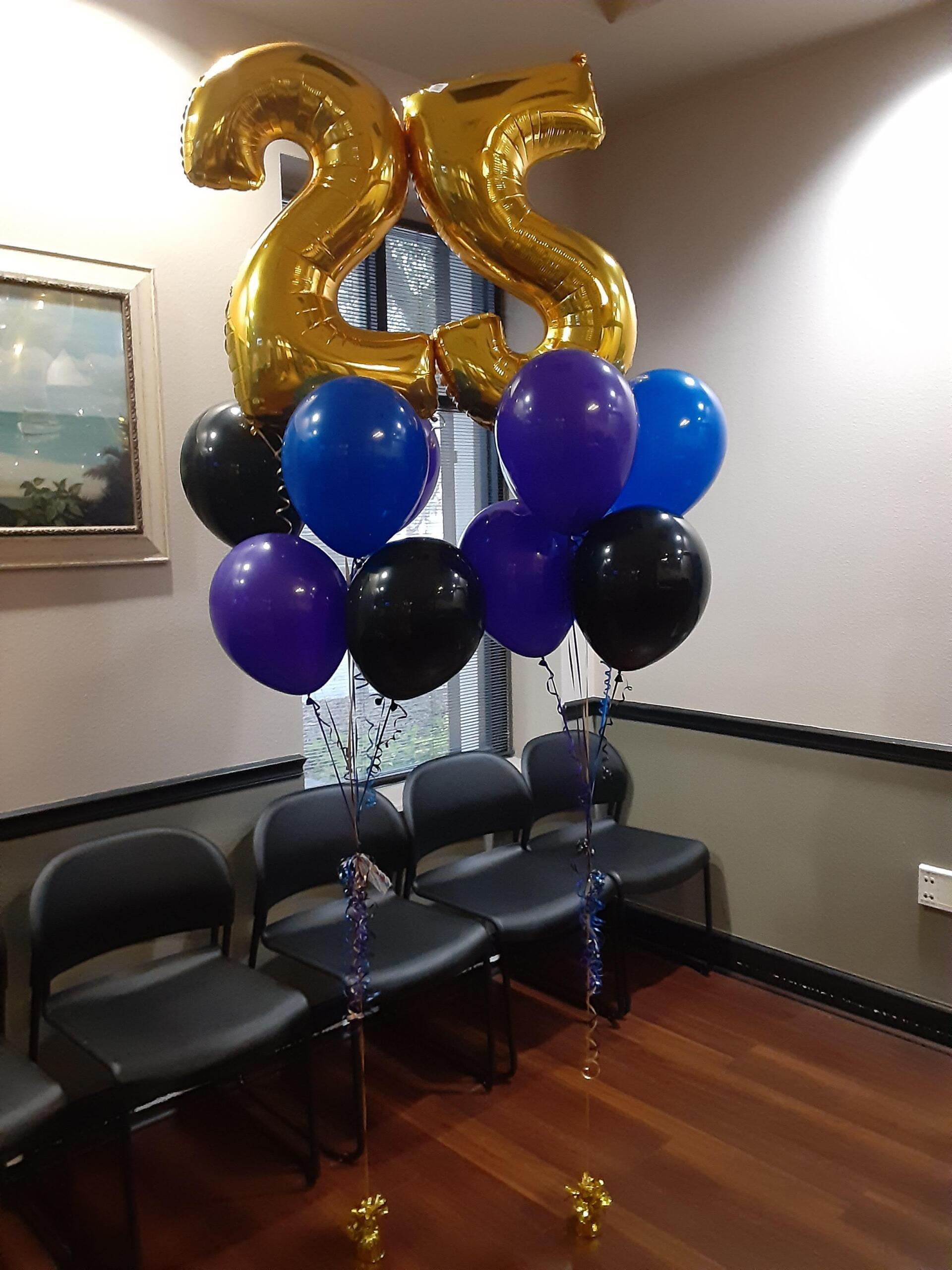A bunch of balloons with a gold number 25 on top of them