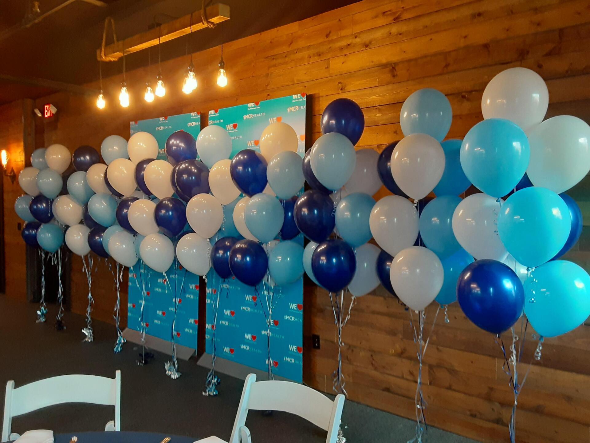 A bunch of blue and white balloons are lined up against a wooden wall