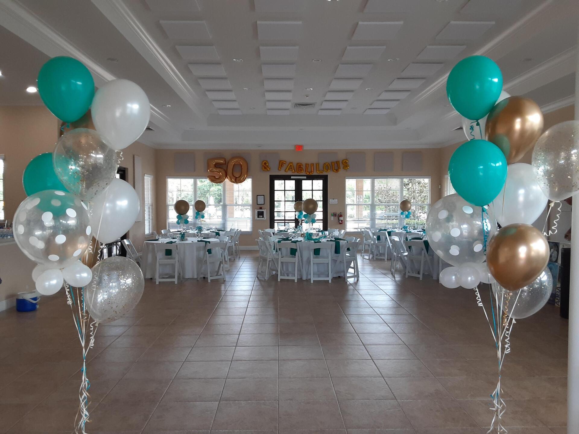 A large room with tables and chairs decorated with balloons.