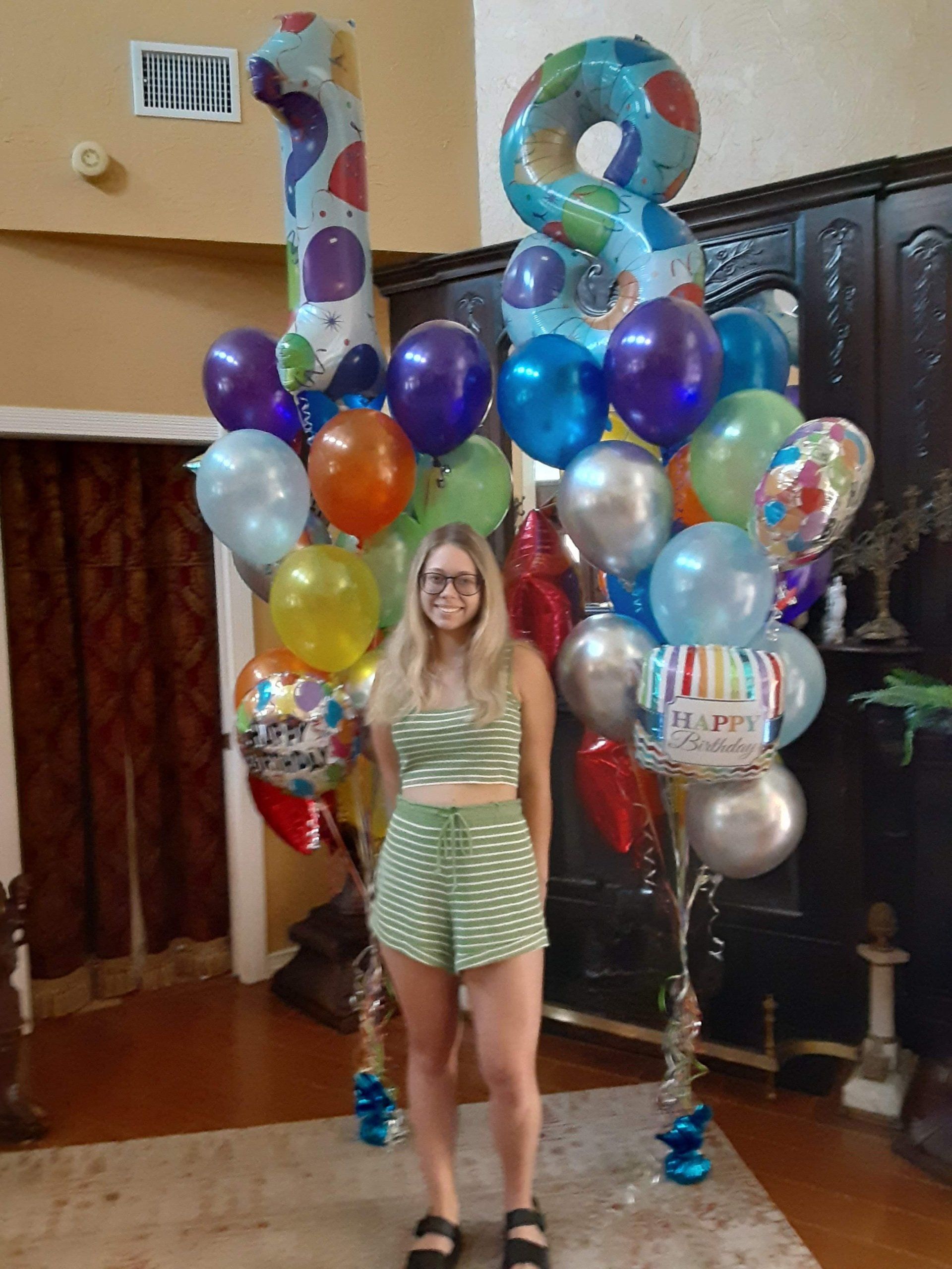 A woman is standing in front of a bunch of balloons.