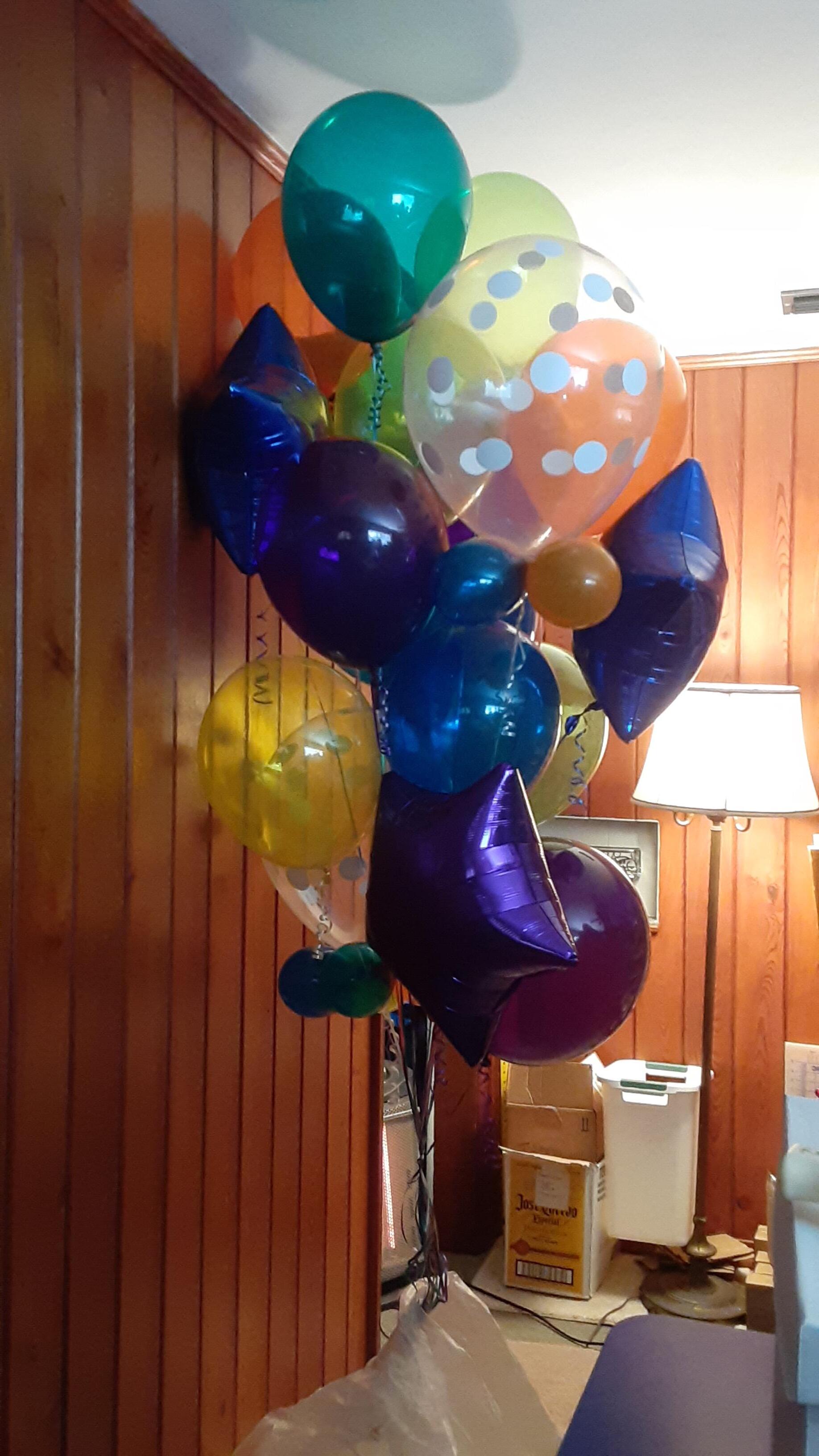 A bunch of balloons are hanging on a wooden wall.