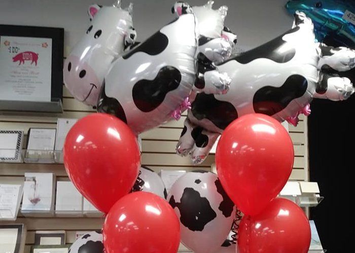 A bunch of cow shaped balloons and red balloons