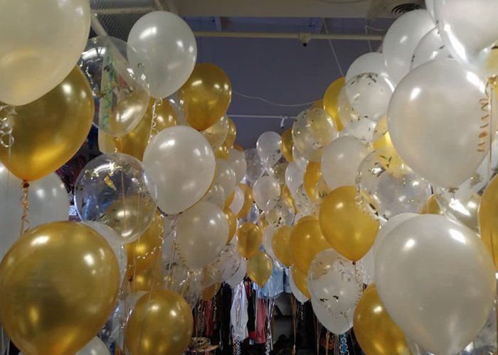 A bunch of gold and white balloons hanging from the ceiling
