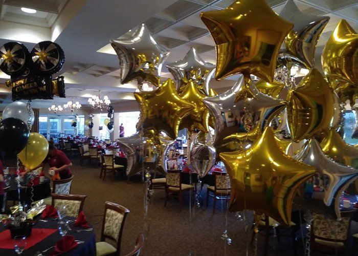 A room filled with tables and chairs and balloons in the shape of stars.