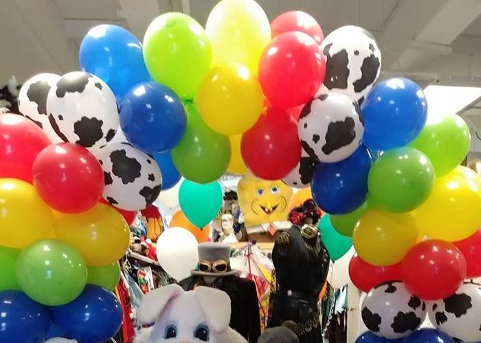 A bunch of colorful balloons with cow print on them