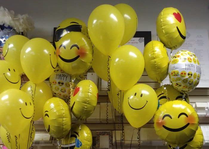 A bunch of yellow balloons with smiley faces on them