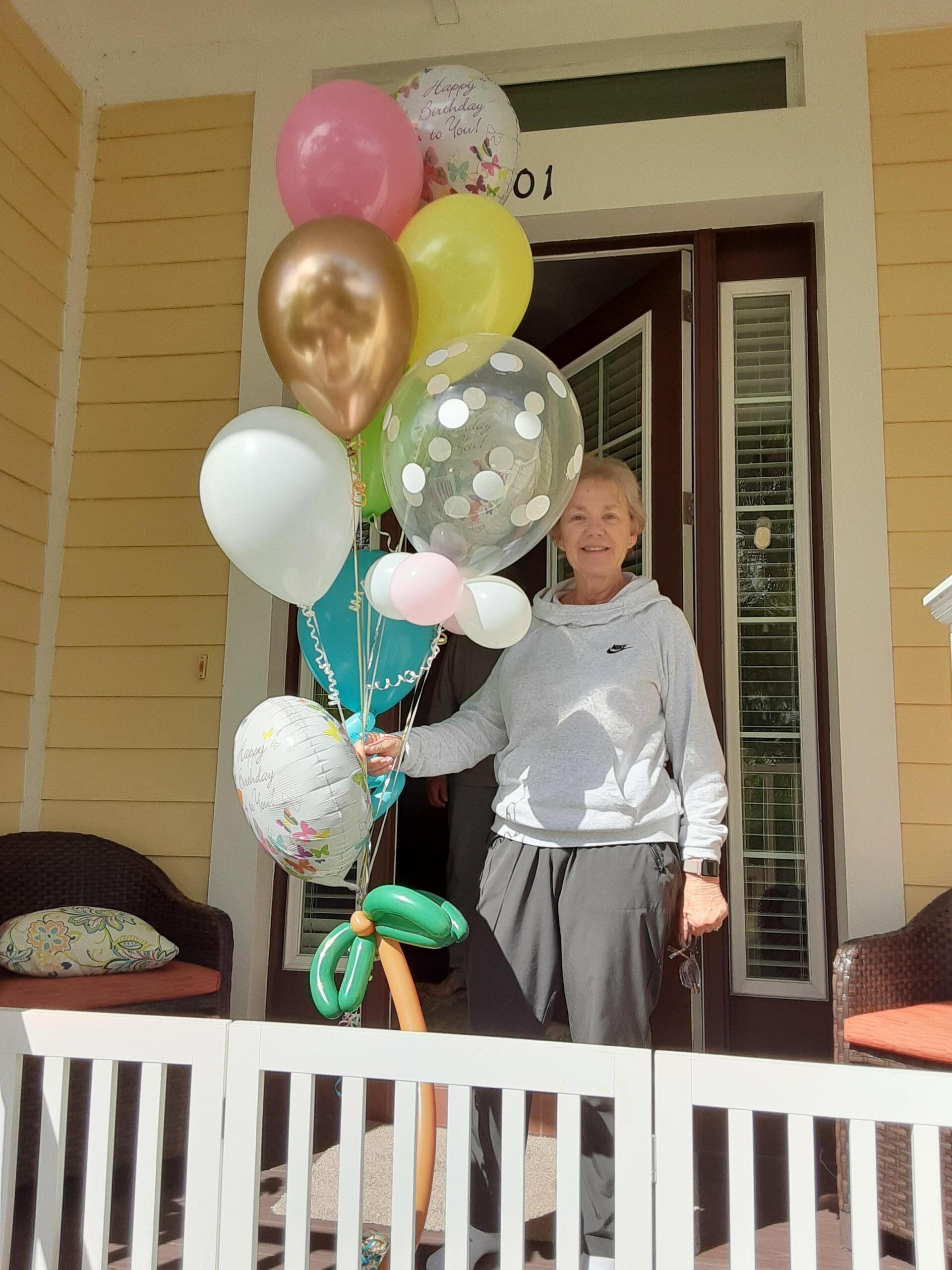 smiling woman with balloons at the front door