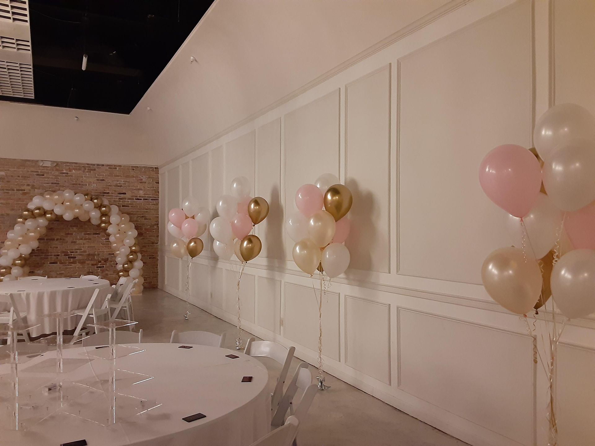 A room with tables and chairs and balloons on the wall.