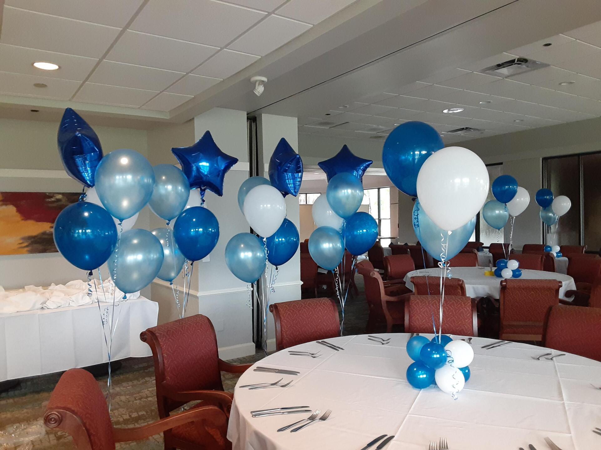A room with tables and chairs decorated with blue and white balloons
