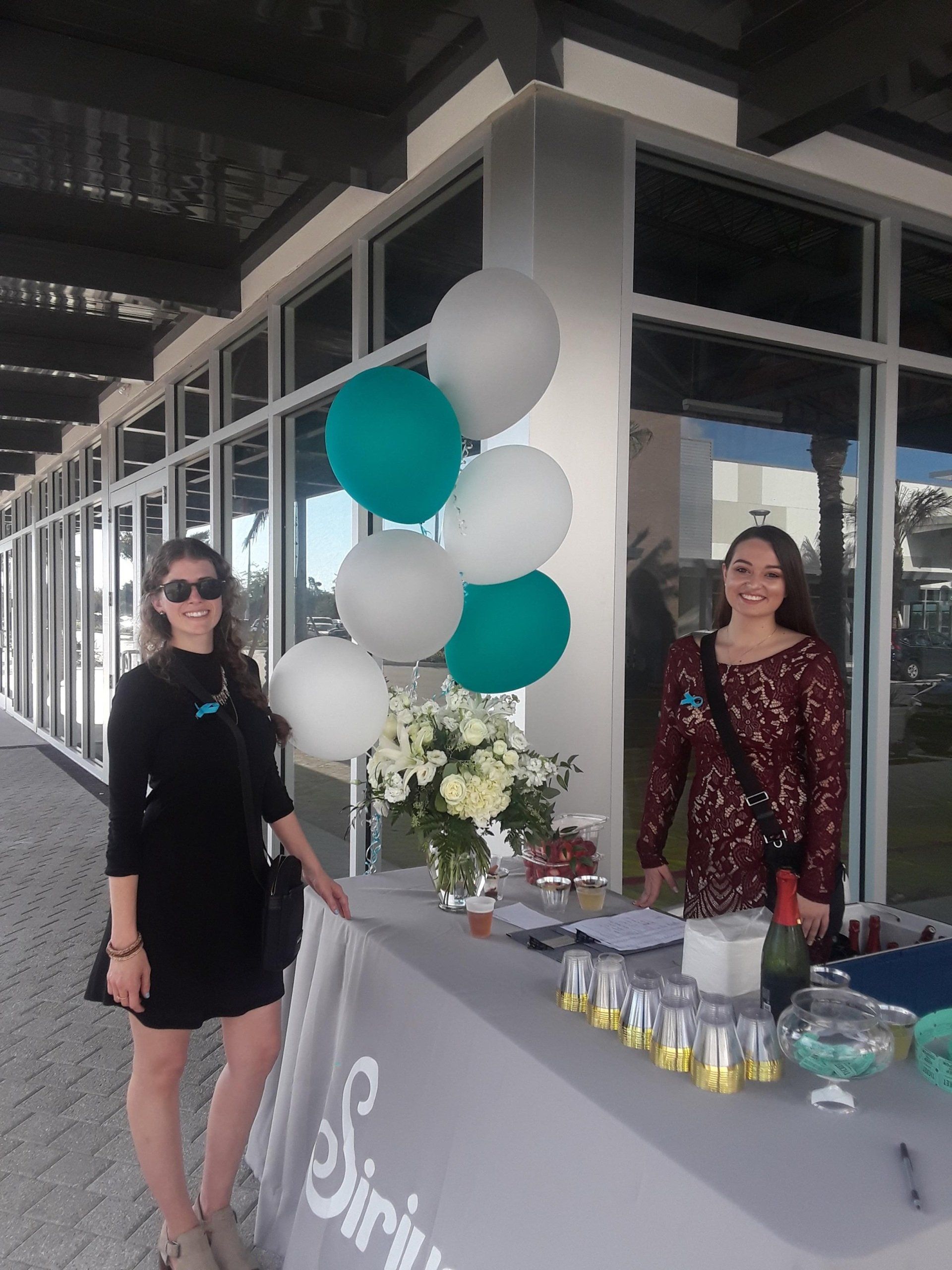 Two women standing in front of a table with balloons and flowers