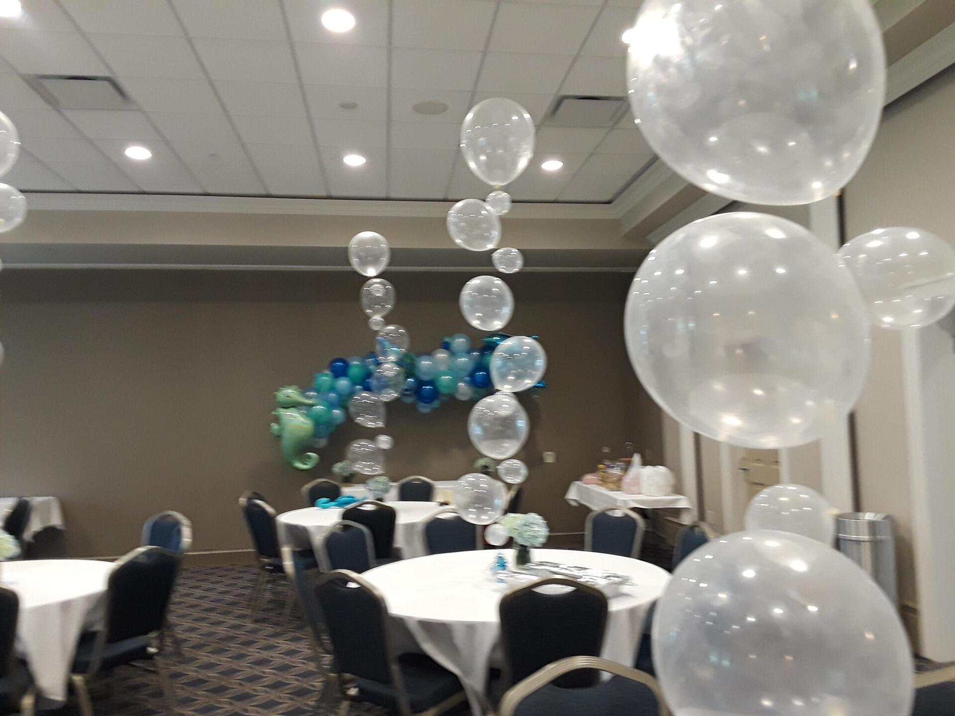 A room with tables and chairs and balloons hanging from the ceiling