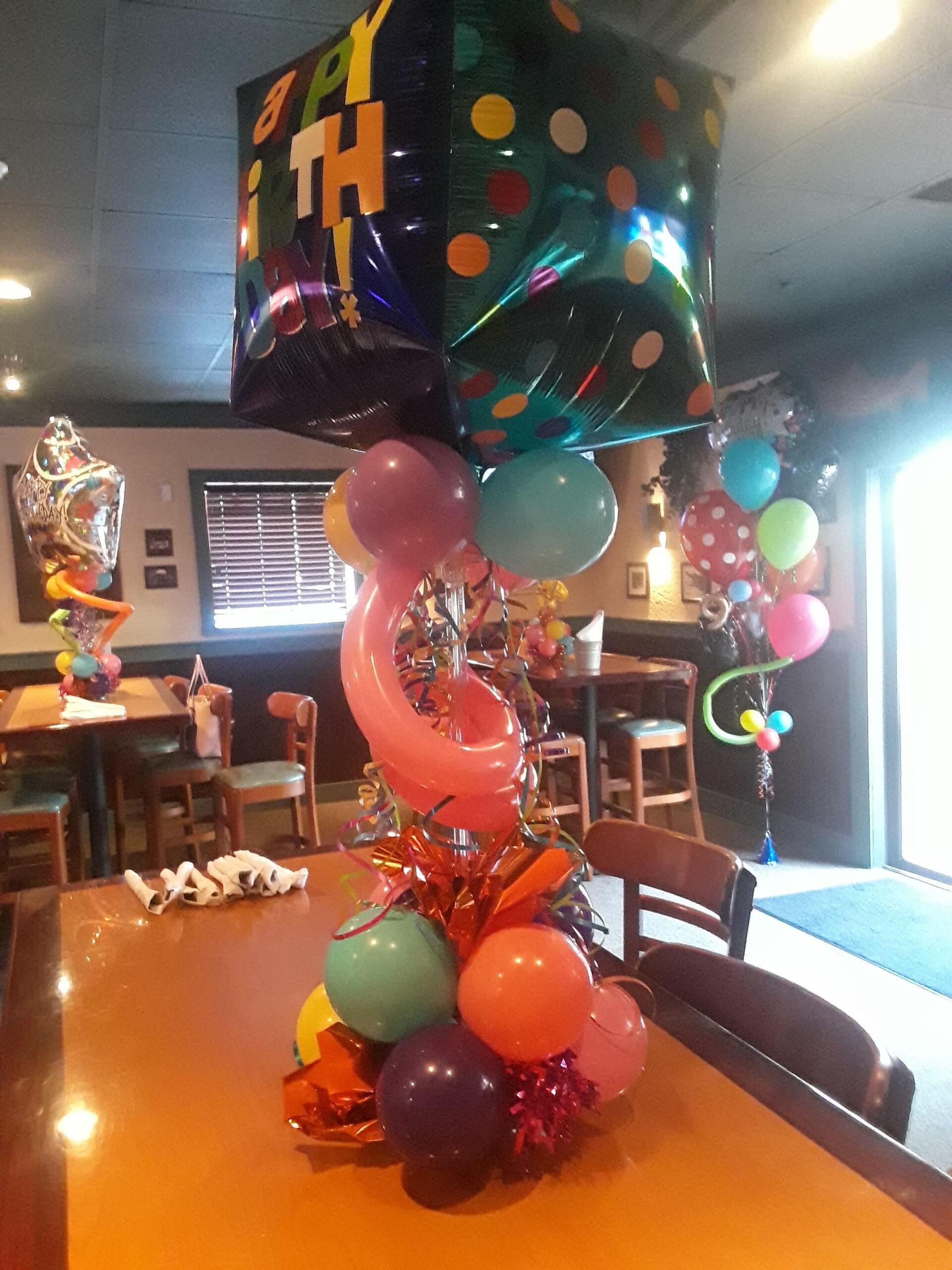 A table is decorated with balloons and a birthday balloon