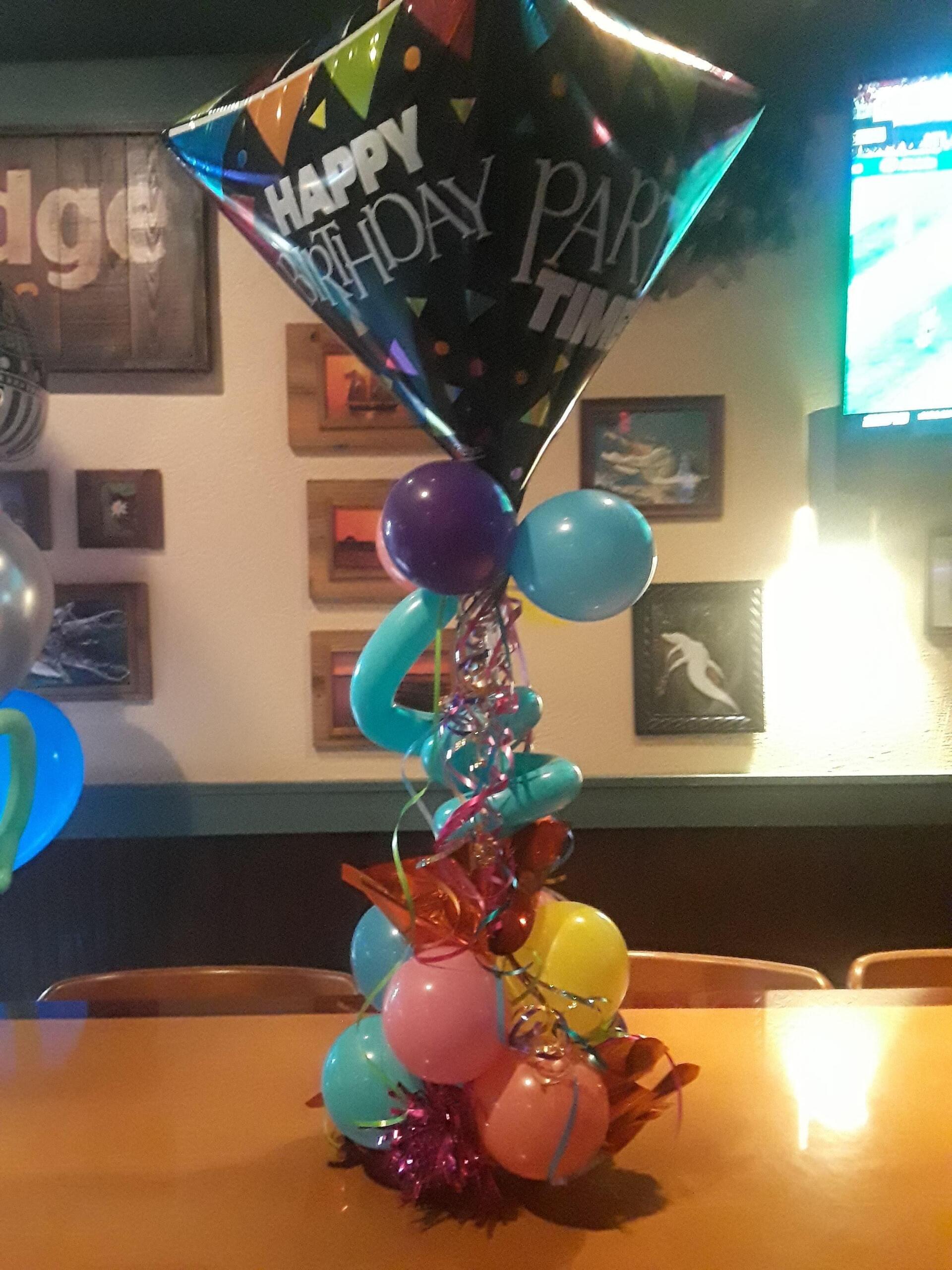 A table with balloons and a balloon that says happy birthday tim
