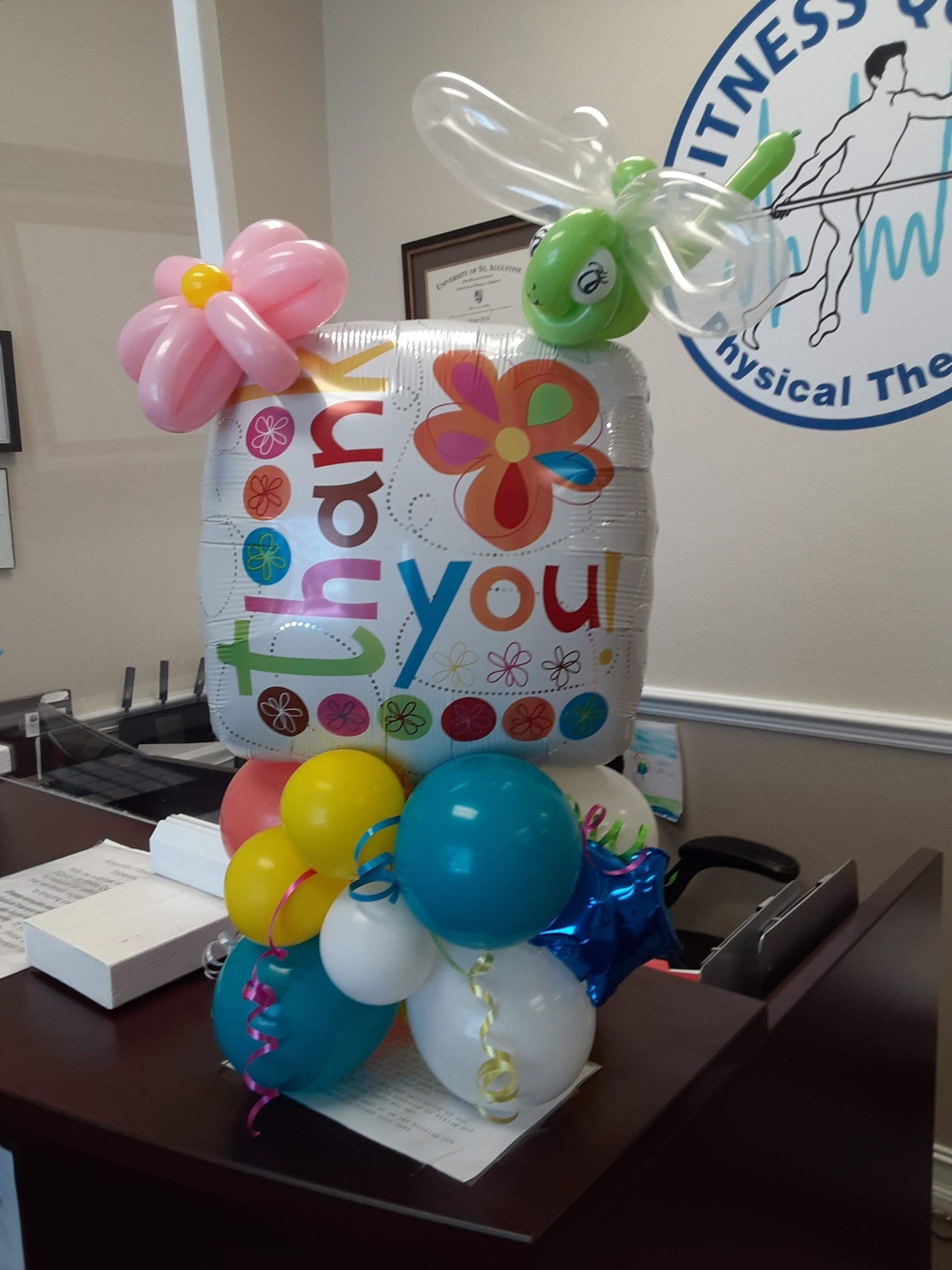 A balloon that says thank you is sitting on a desk