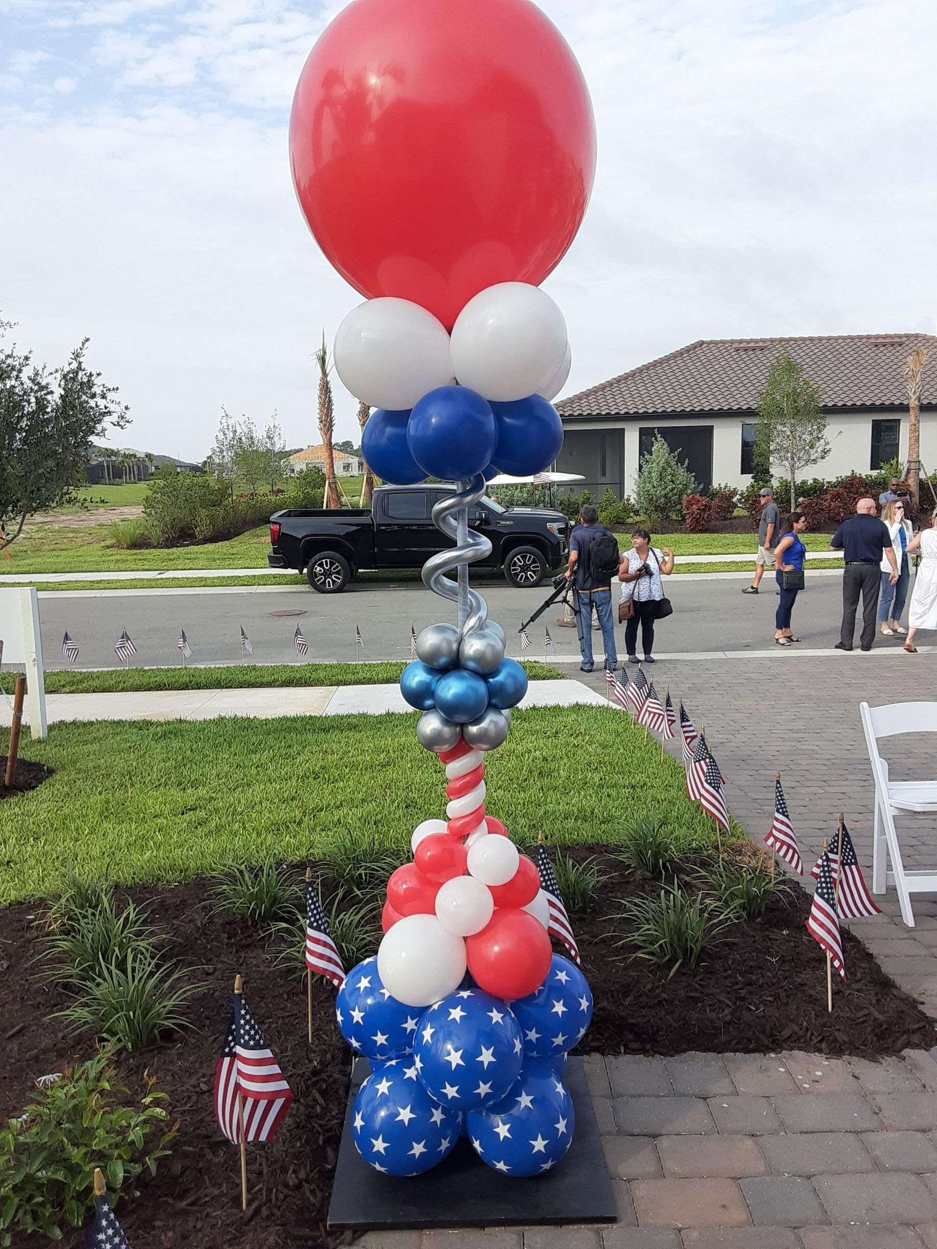 A red , white and blue balloon tower is sitting in front of a house.