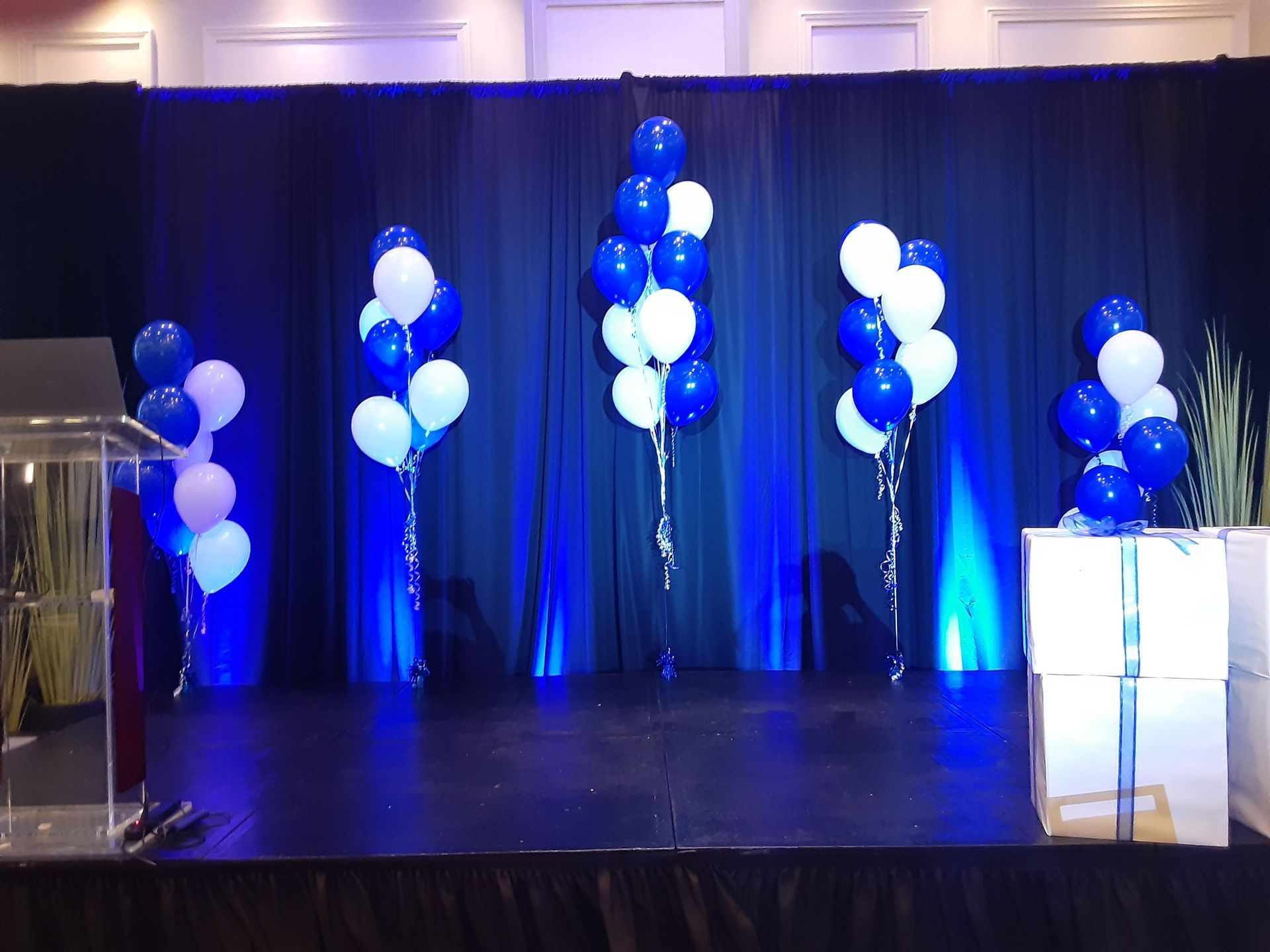 A stage with blue and white balloons on it