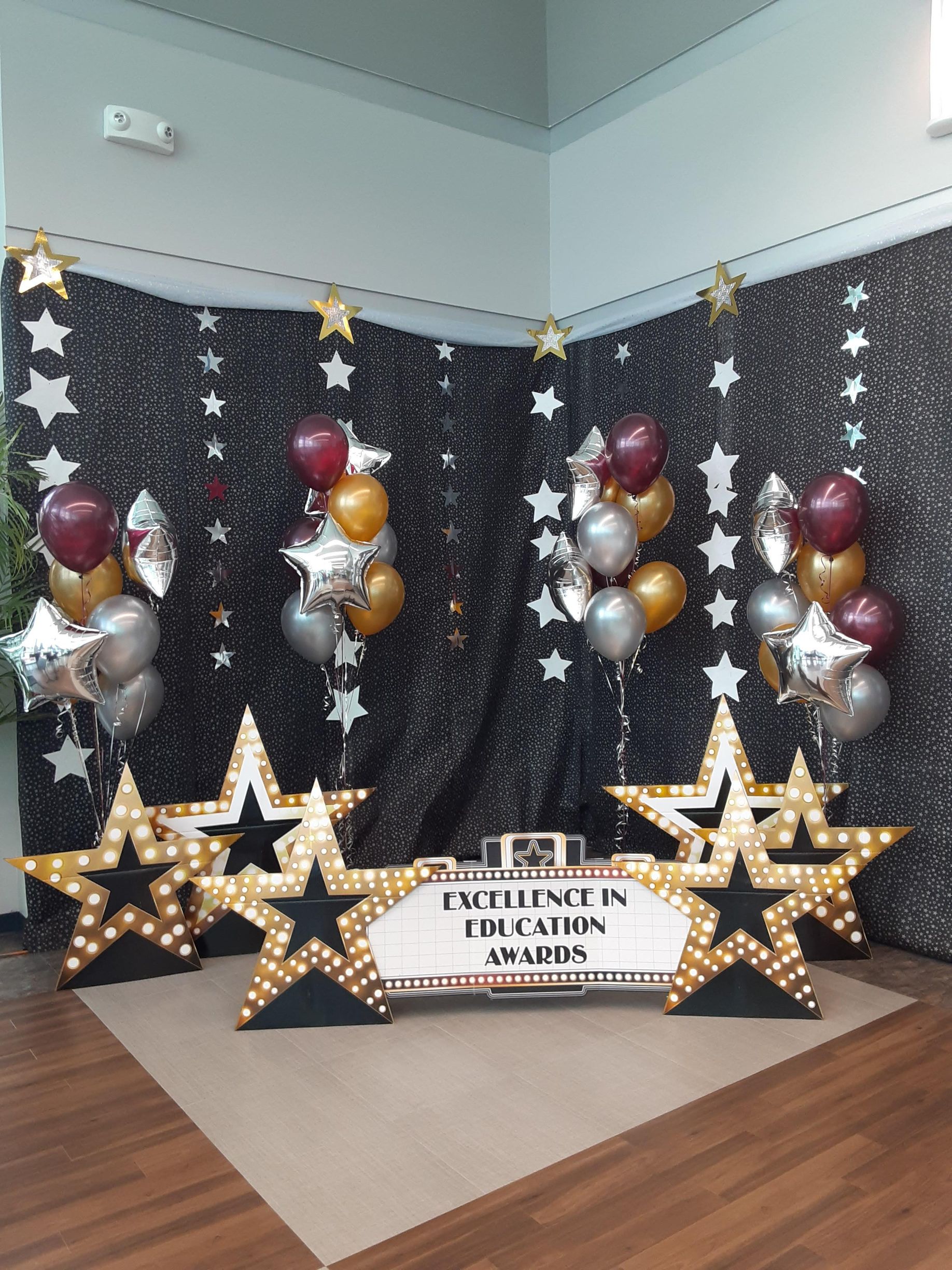 A room decorated with balloons , stars and a sign.