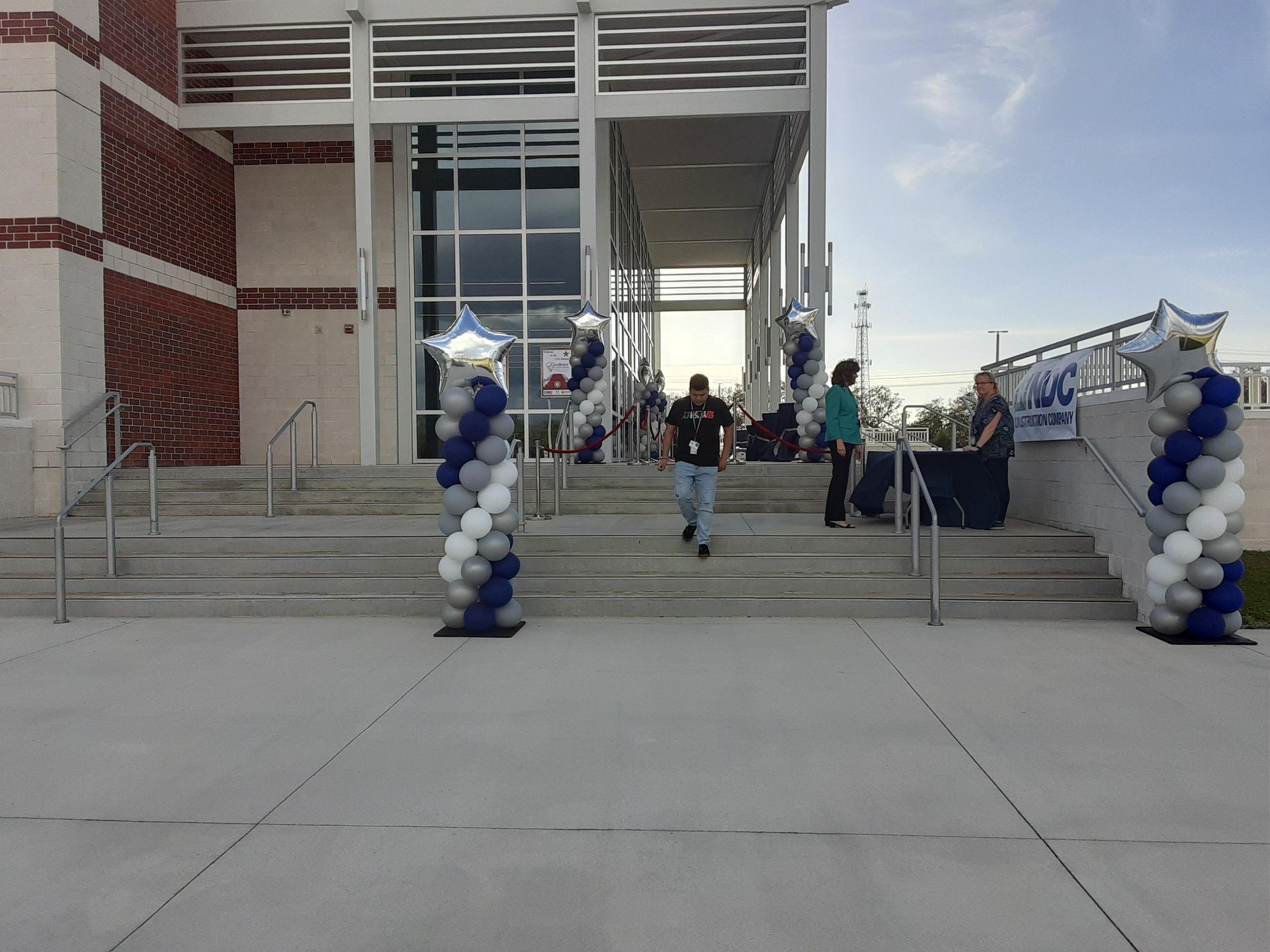 A building with balloons in front of it and people walking down the stairs