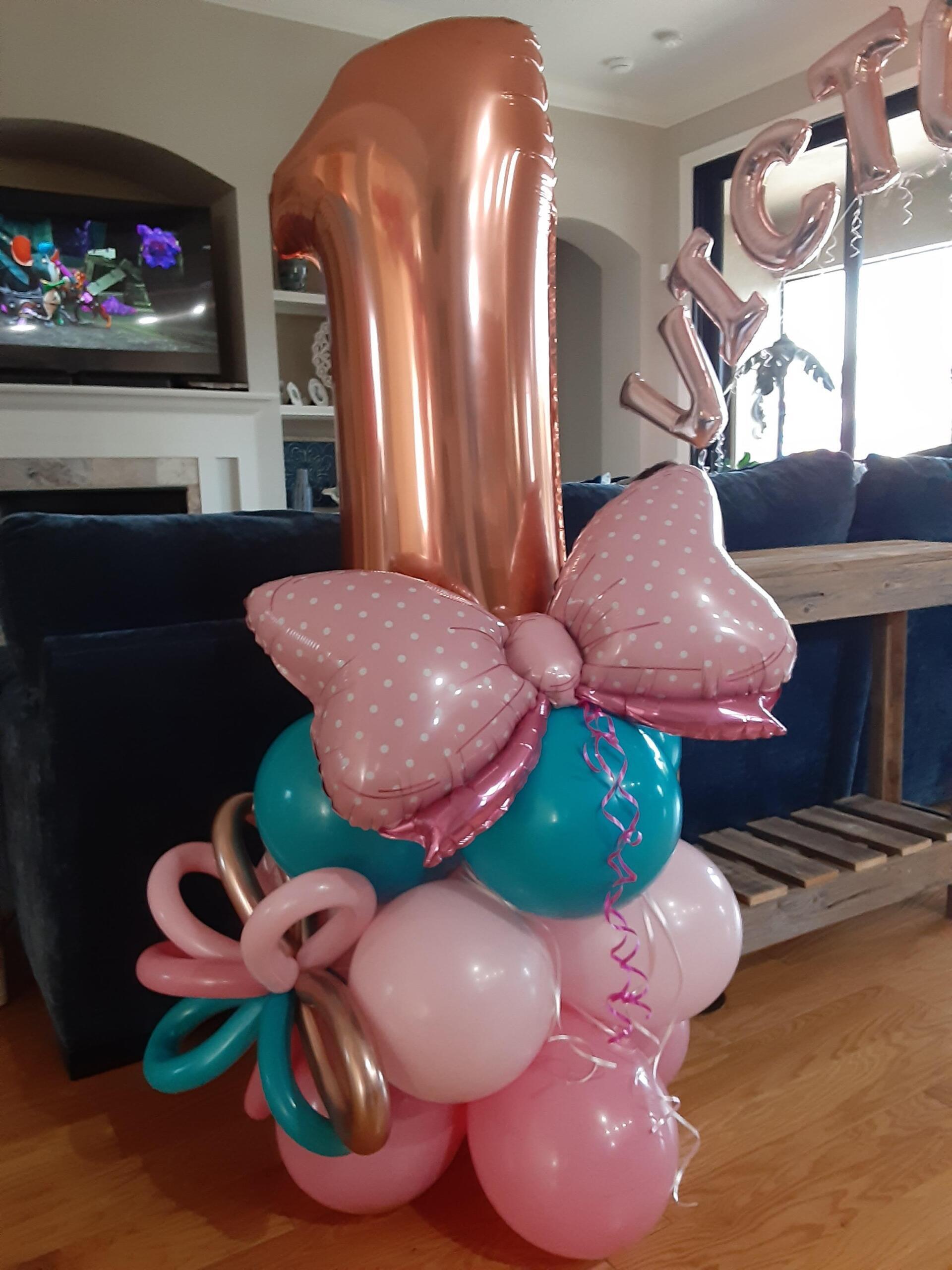 A number one balloon is surrounded by pink and blue balloons.