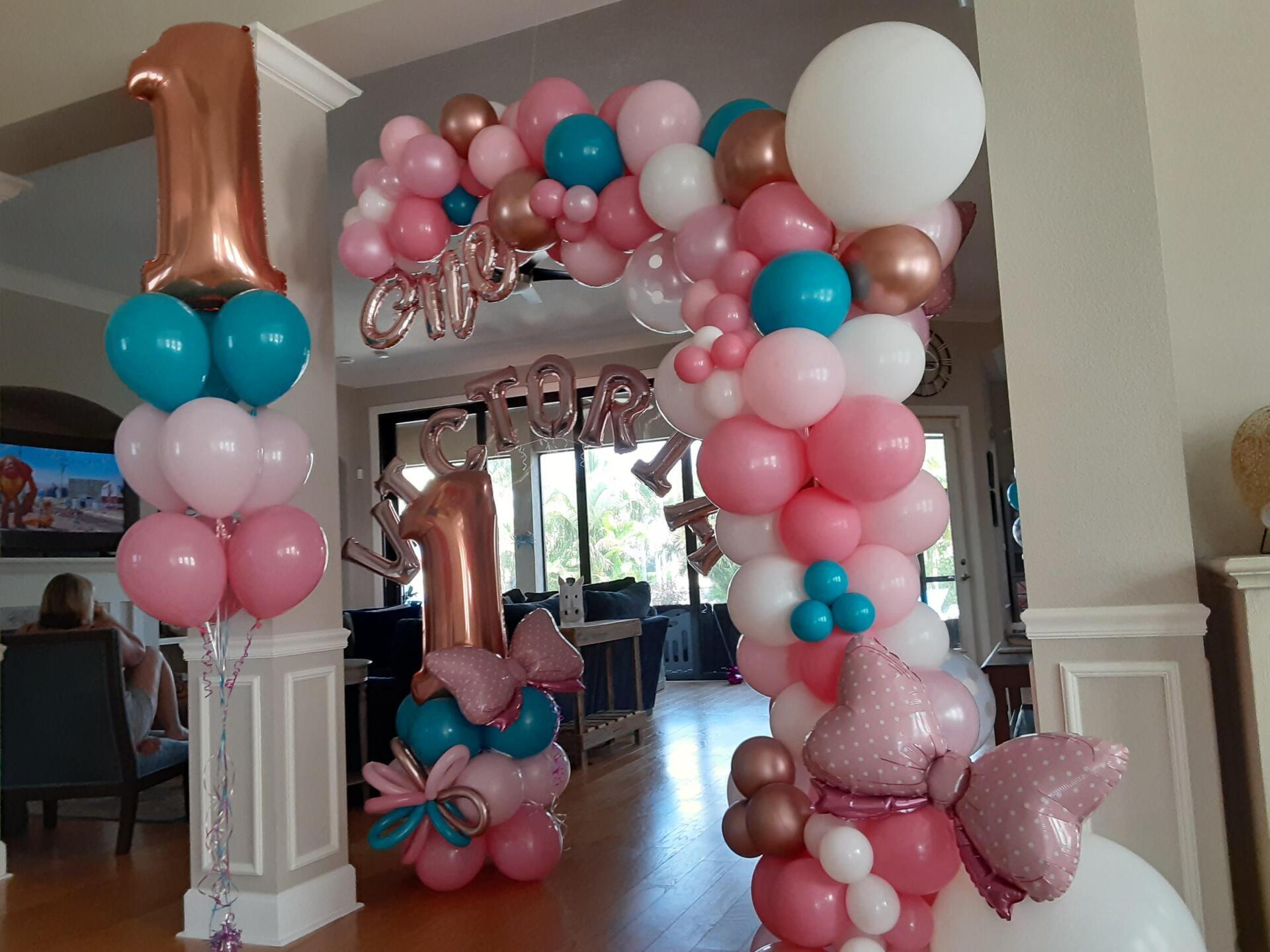 A room decorated with balloons for a girl 's first birthday.