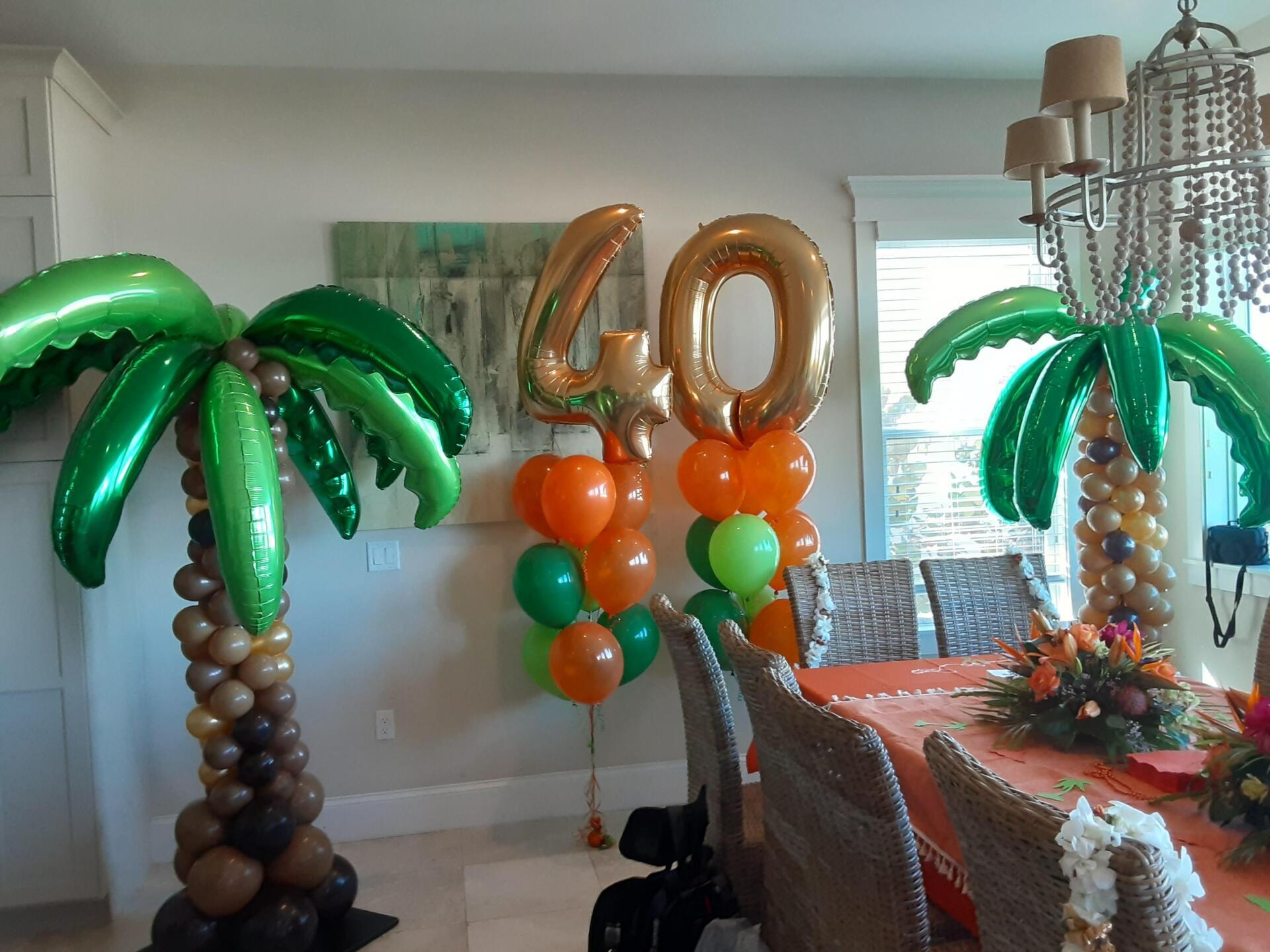 A dining room decorated with palm trees and balloons for a 40th birthday