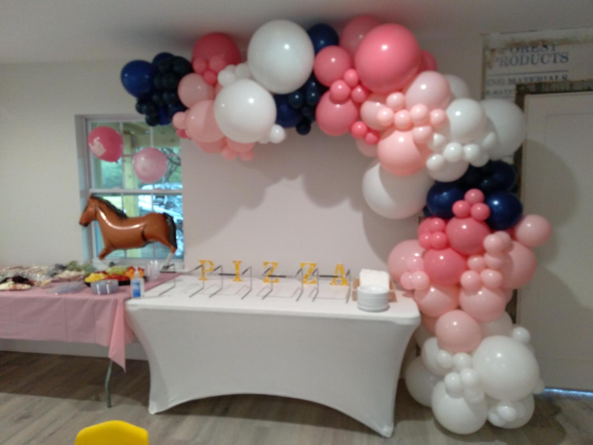 A table with balloons on it and a horse balloon in the background.