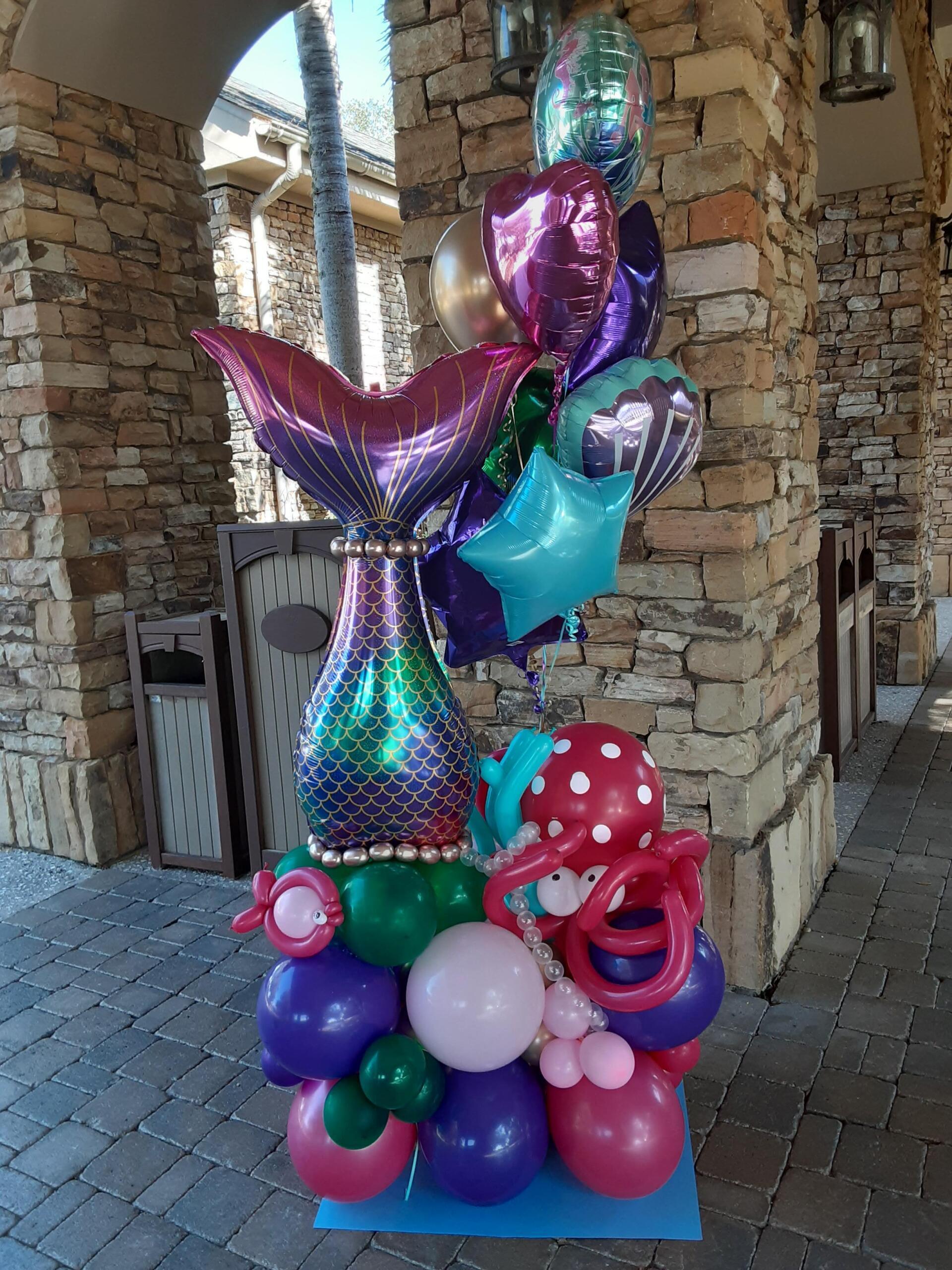 A bunch of balloons with a mermaid tail on top of them.