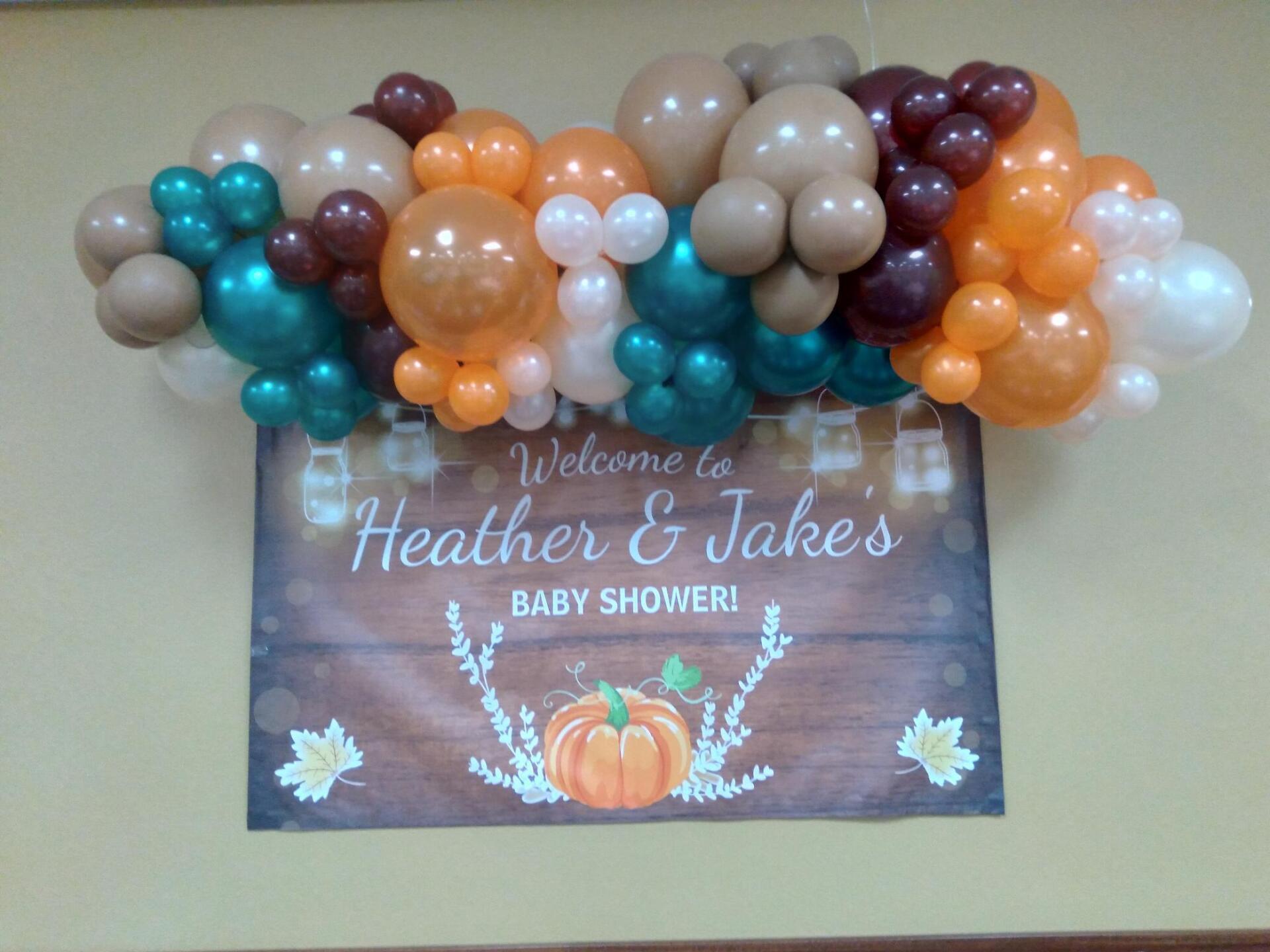 A welcome sign for a baby shower with balloons hanging from the ceiling.