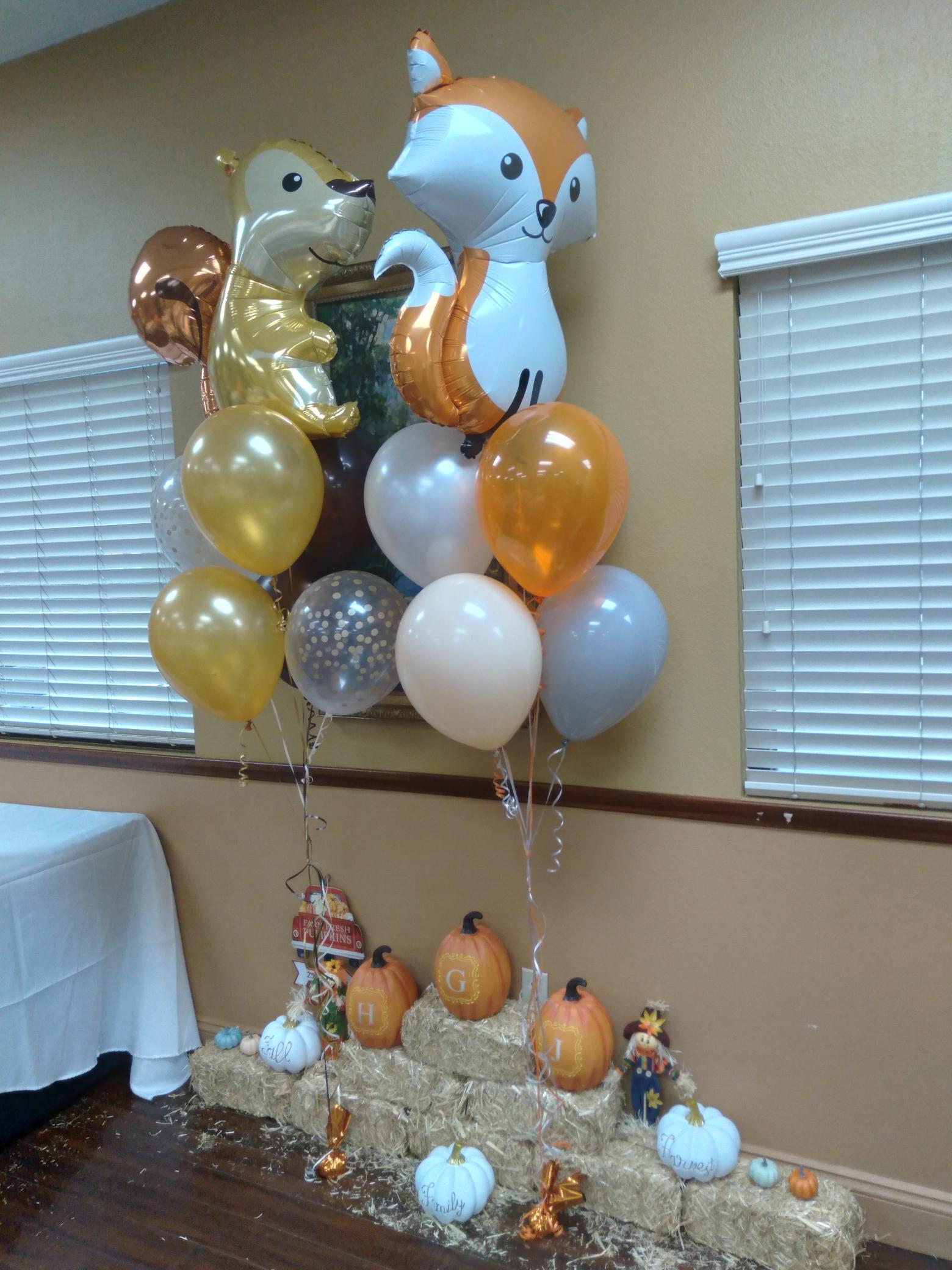A bunch of balloons are sitting on top of a pile of hay.
