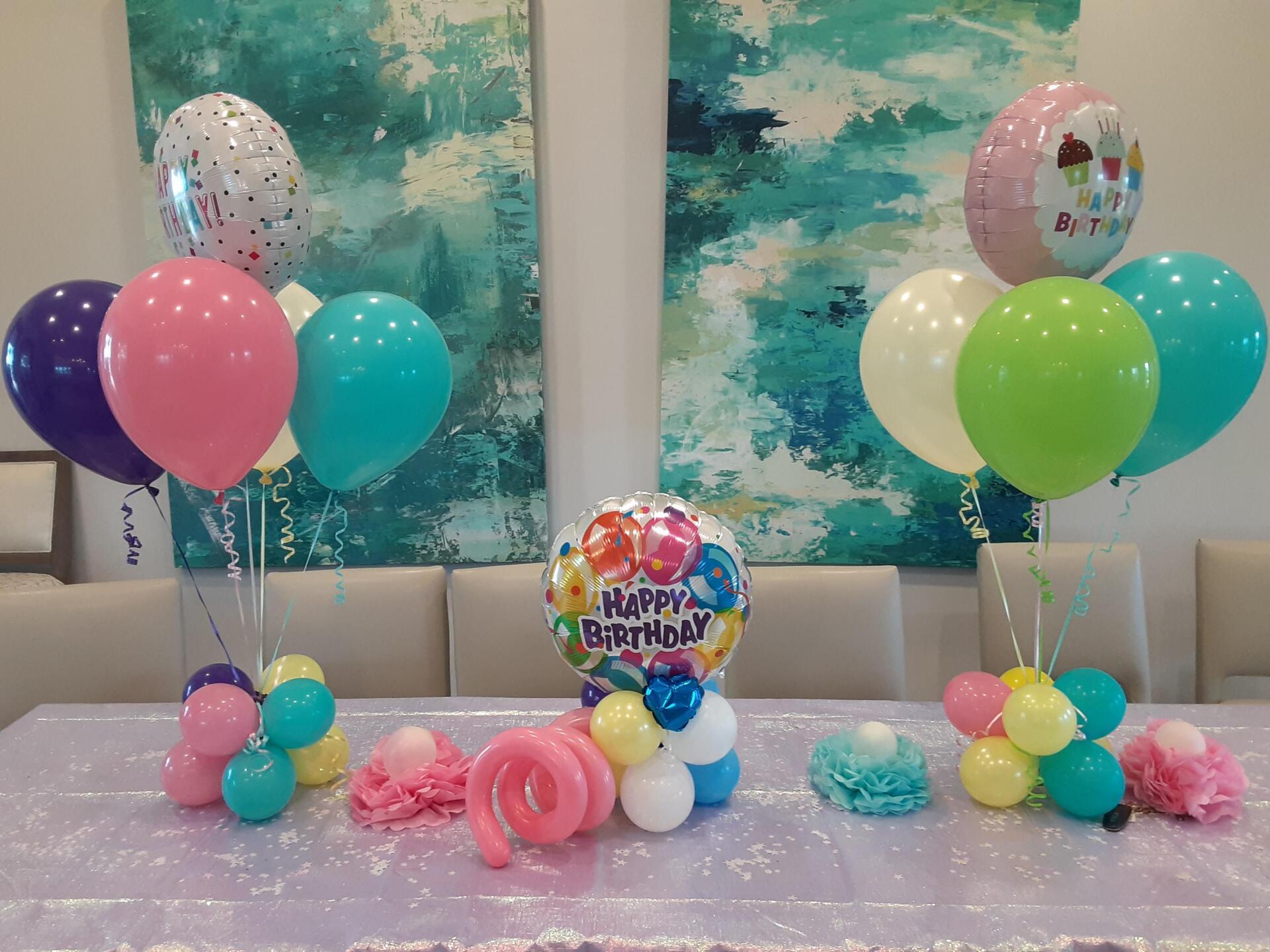A table decorated with balloons and a balloon that says happy birthday