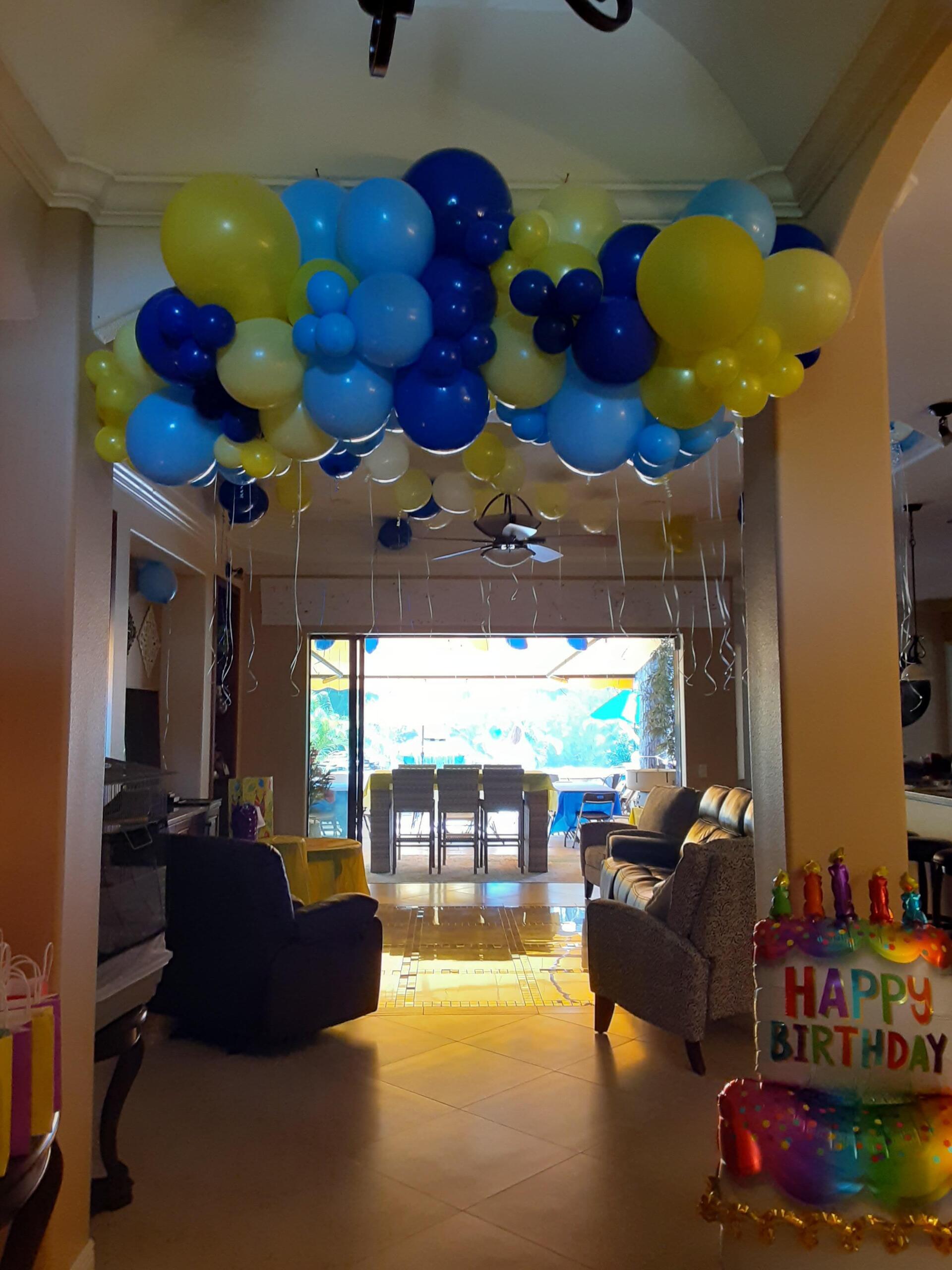 A happy birthday balloon hangs from the ceiling of a living room