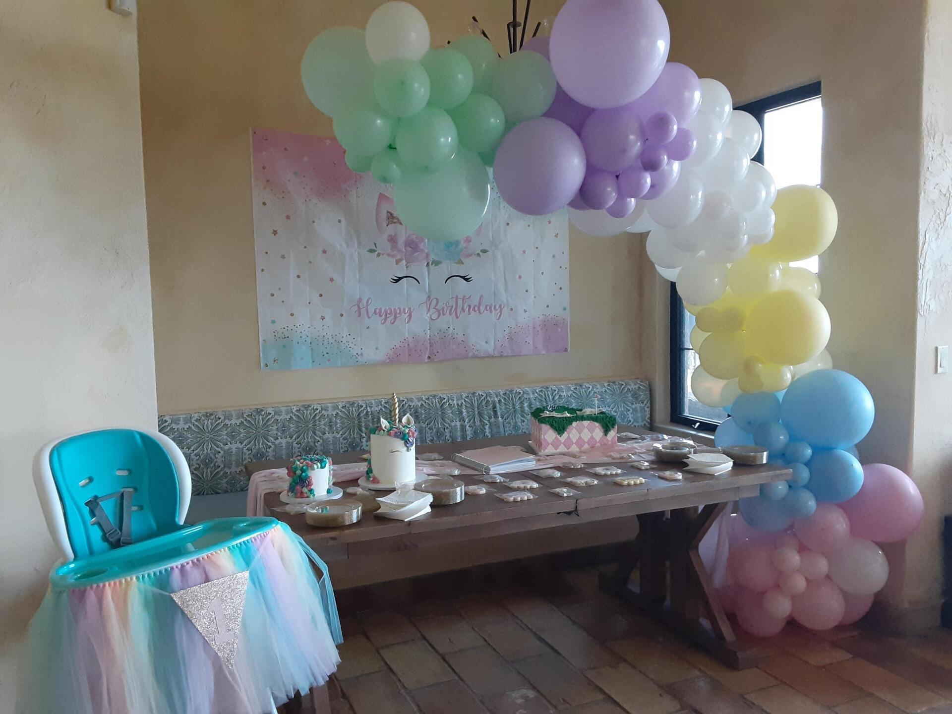 A high chair is sitting next to a table with balloons on it.