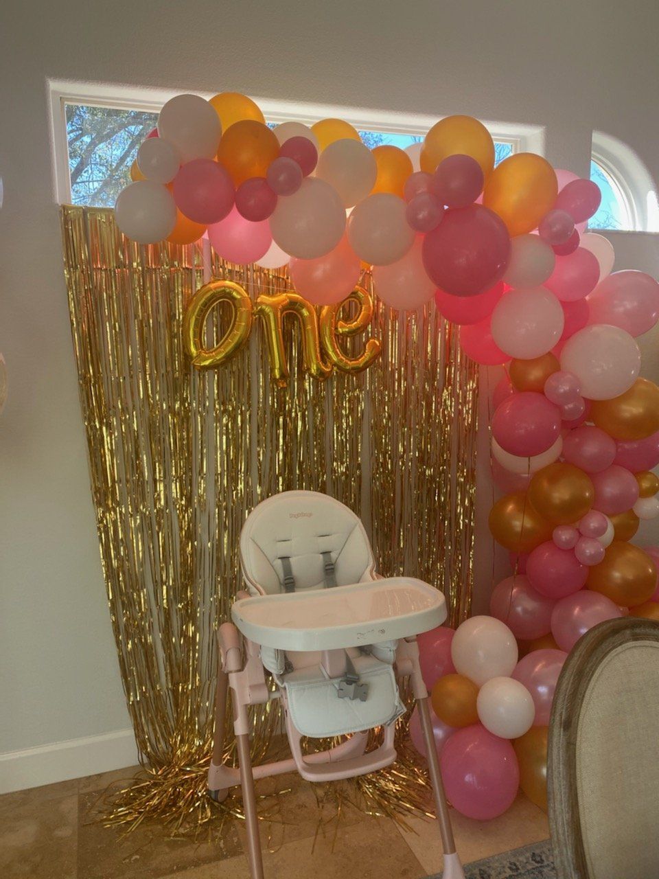 A high chair is sitting in front of a wall covered in balloons.