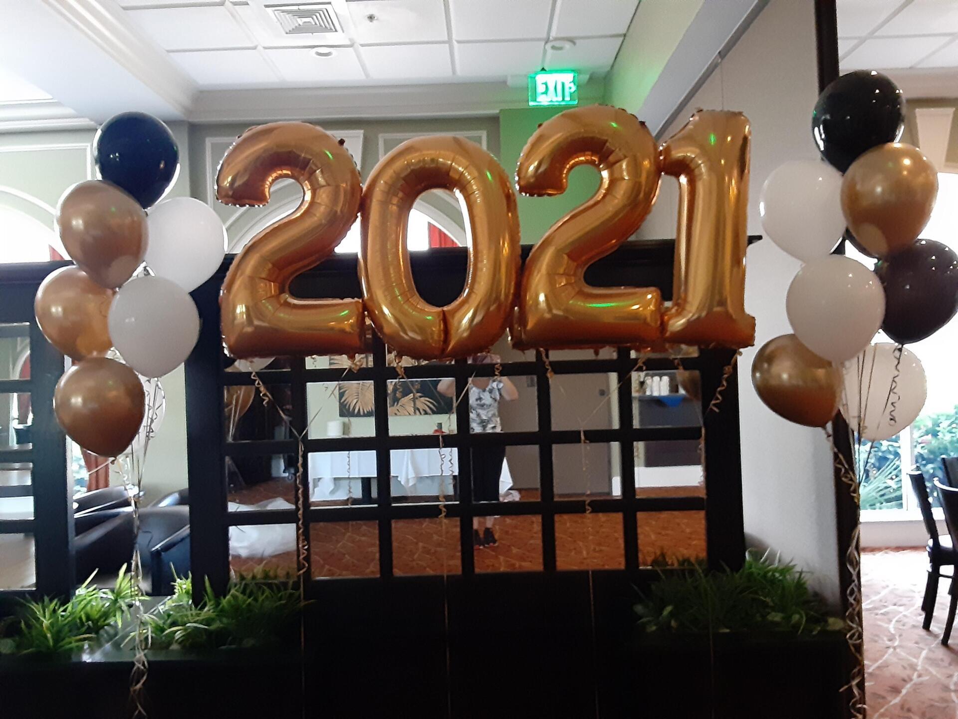 A room decorated with balloons and a sign that says 2021