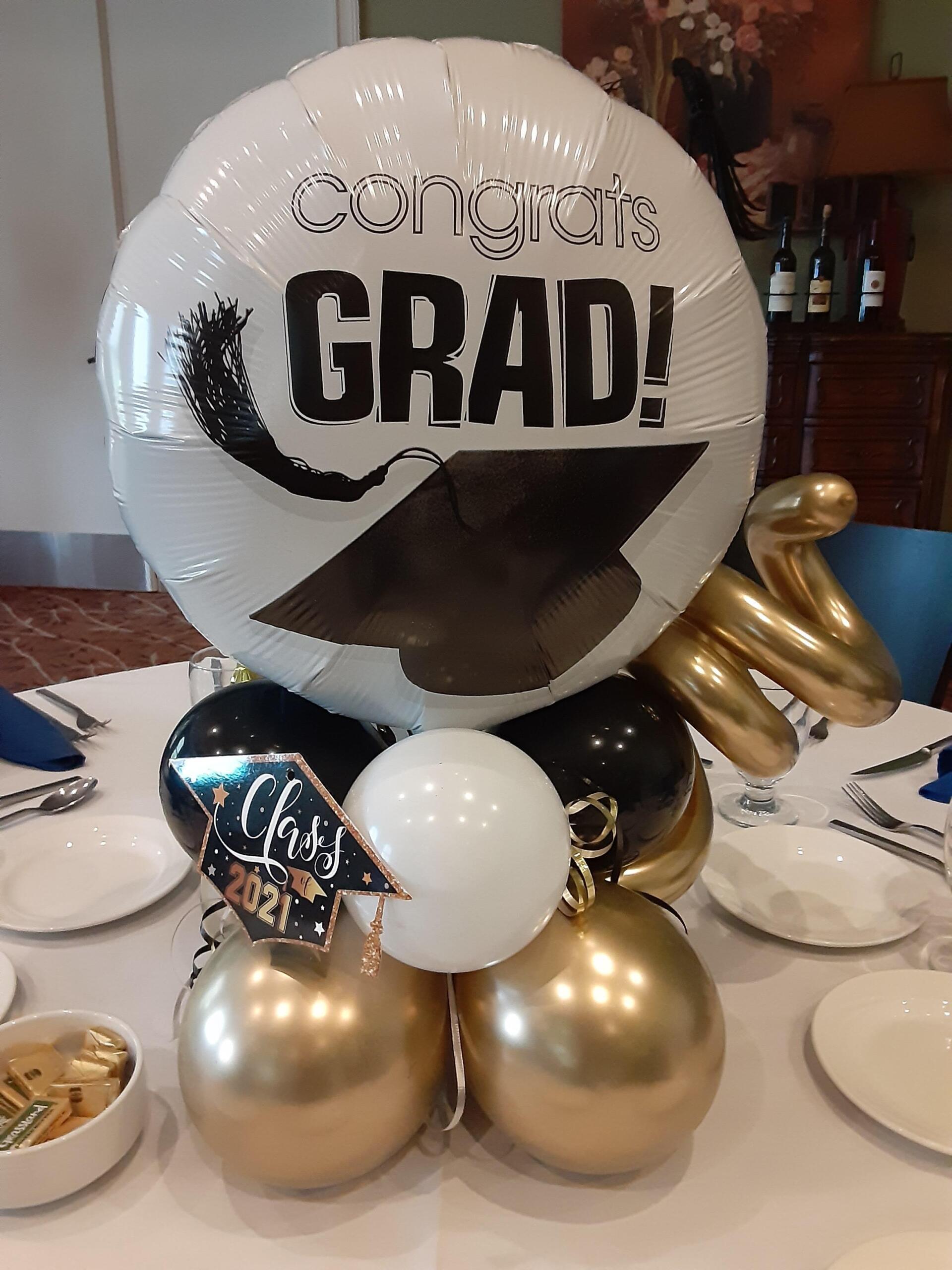 A congratulations grad balloon is sitting on top of a table with balloons.