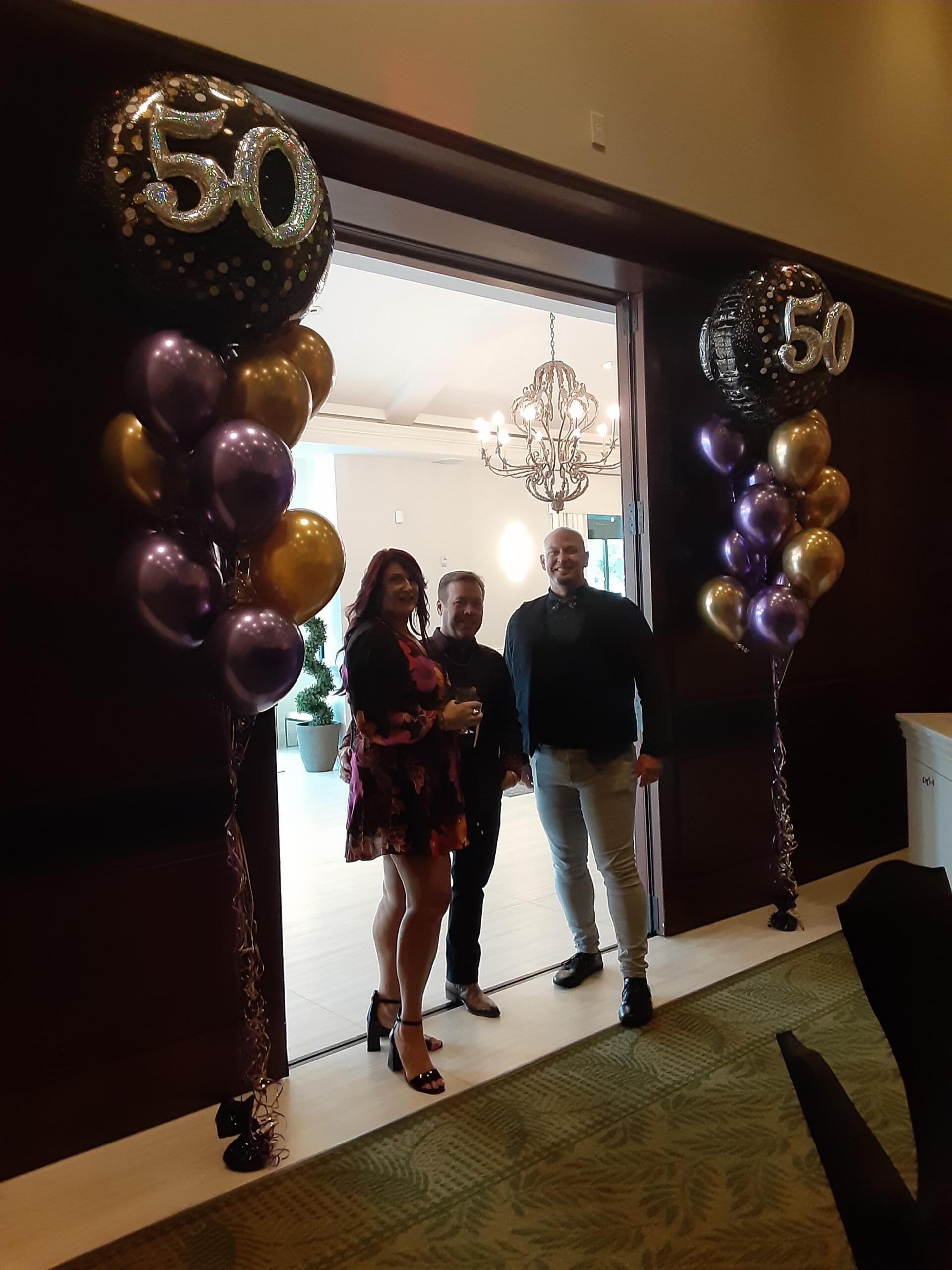 A group of people standing in front of balloons with the number 50 on them.