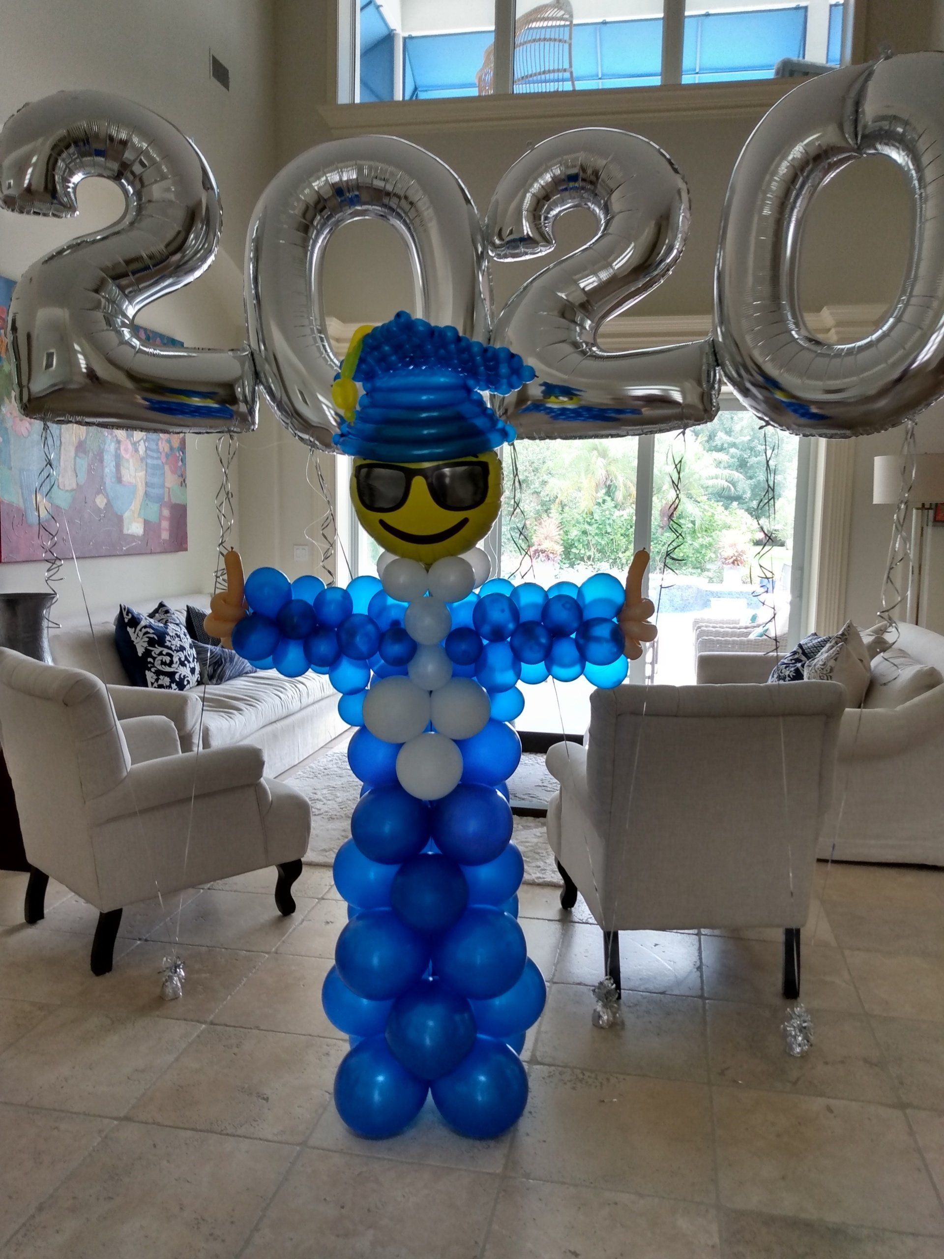 A man made out of blue and white balloons is standing in a living room.