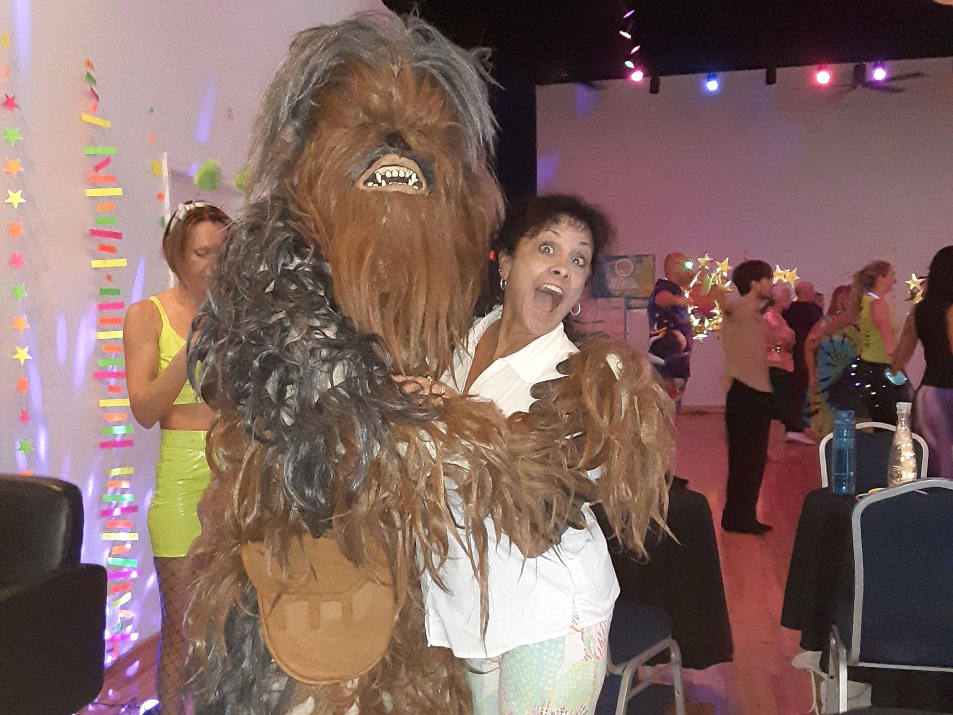 A woman is standing next to a chewbacca costume