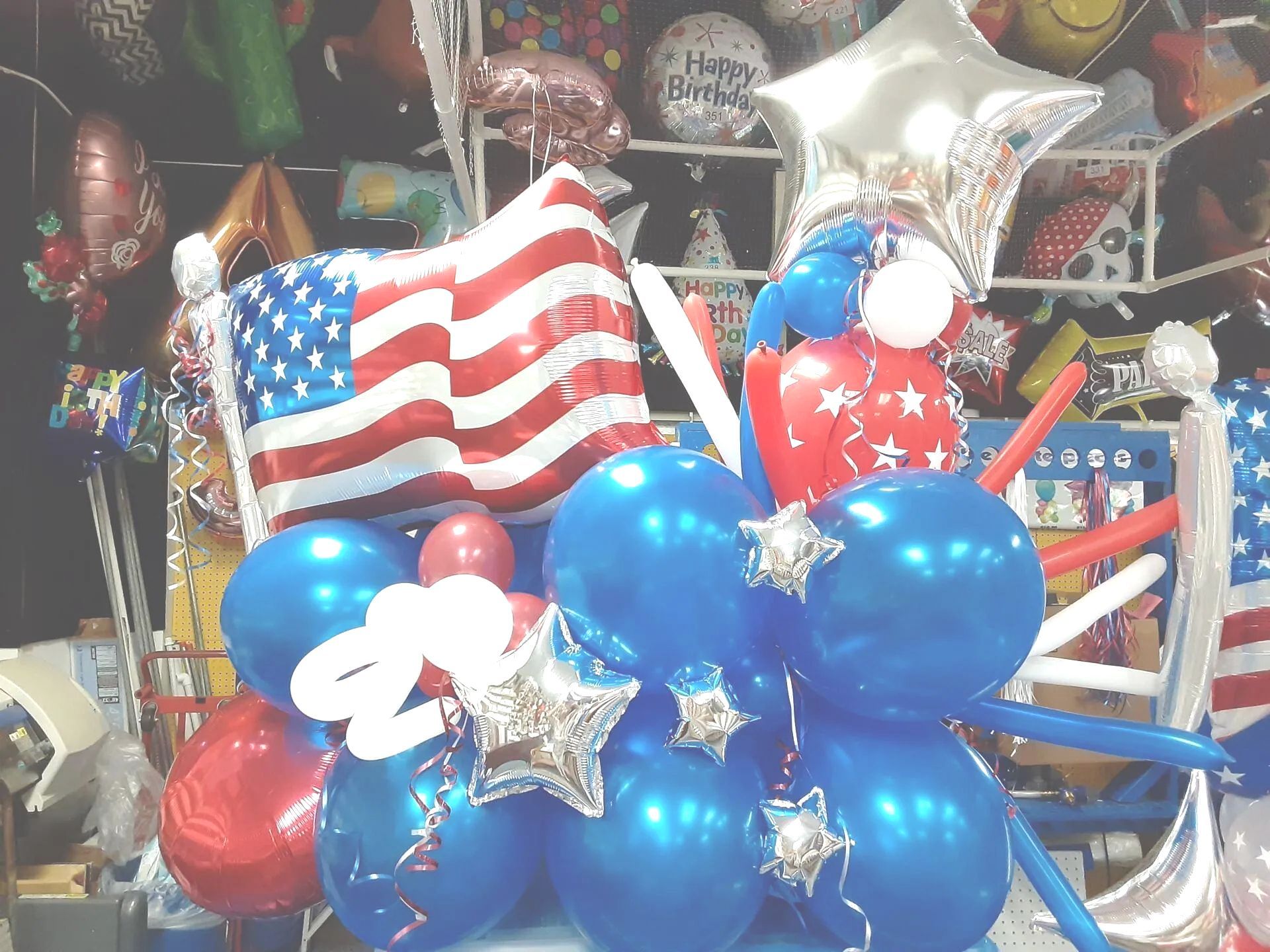 A bunch of red , white and blue balloons with an american flag on top